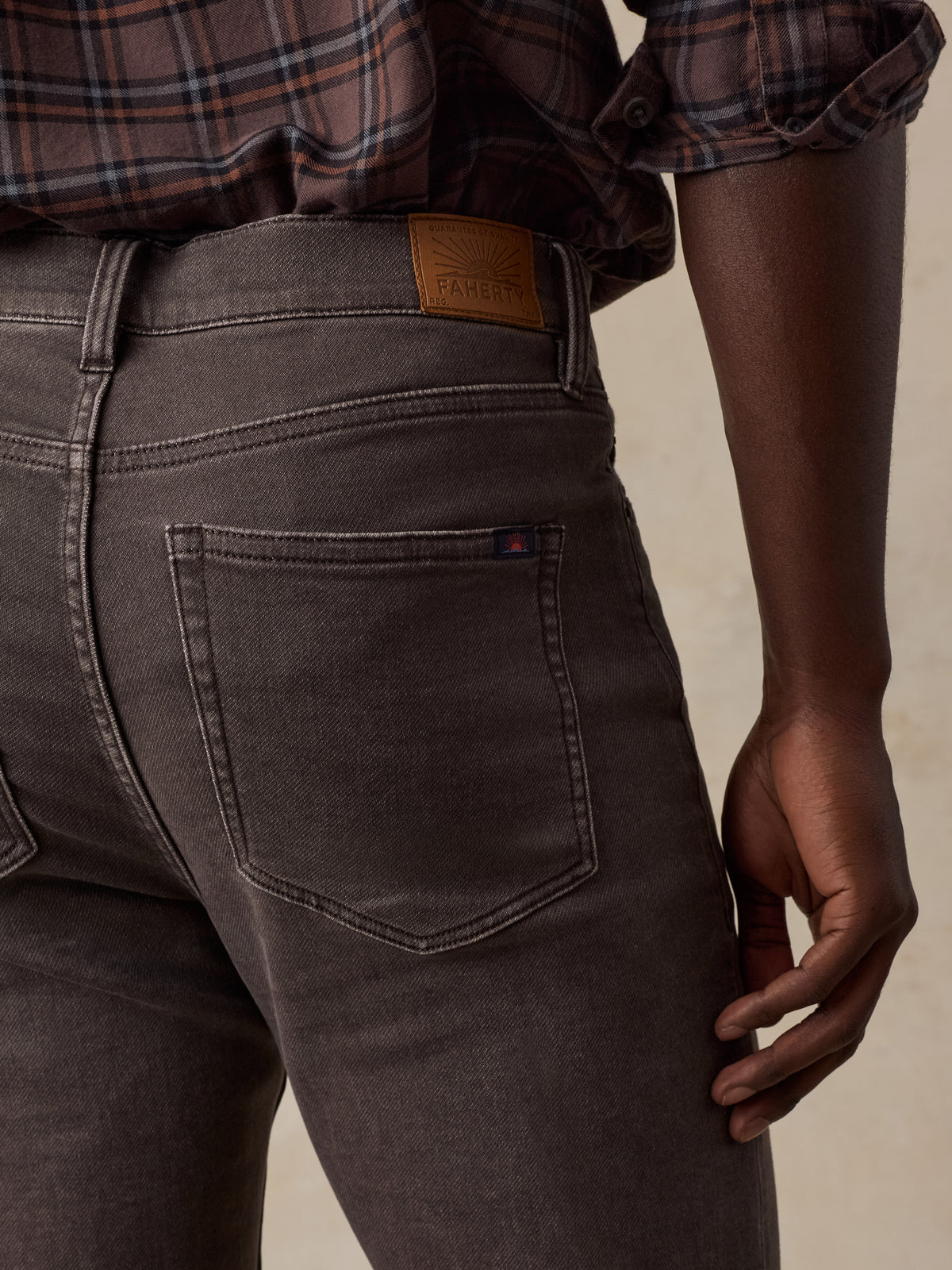 Close up of a man viewed from behind wearing a brown plaid shirt and brown pants, image 4 of 5