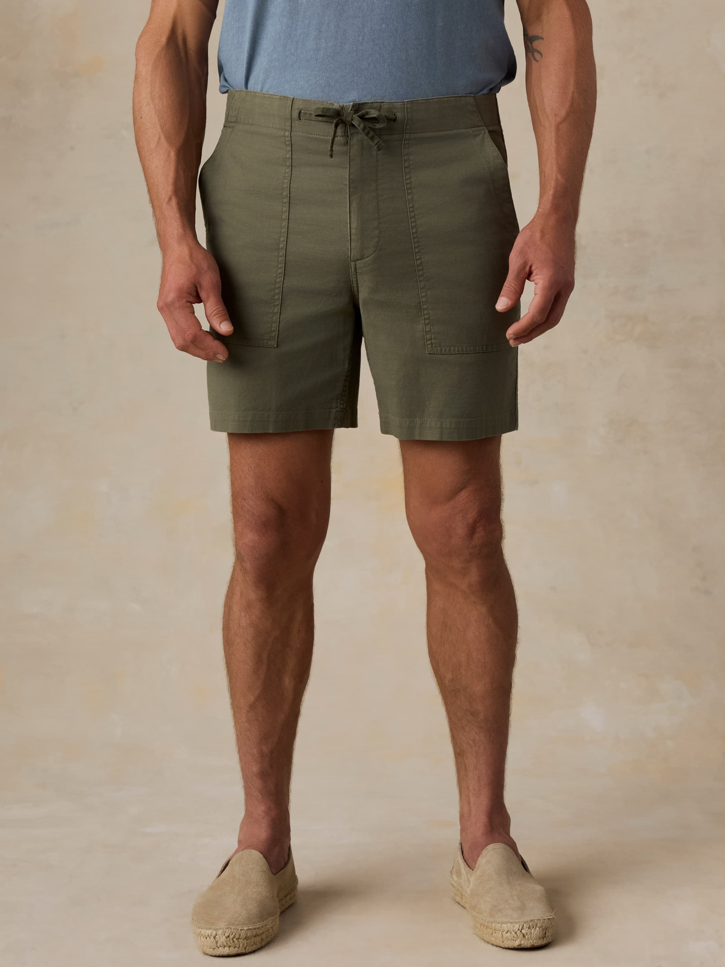 Man wearing olive green shorts on a beige background