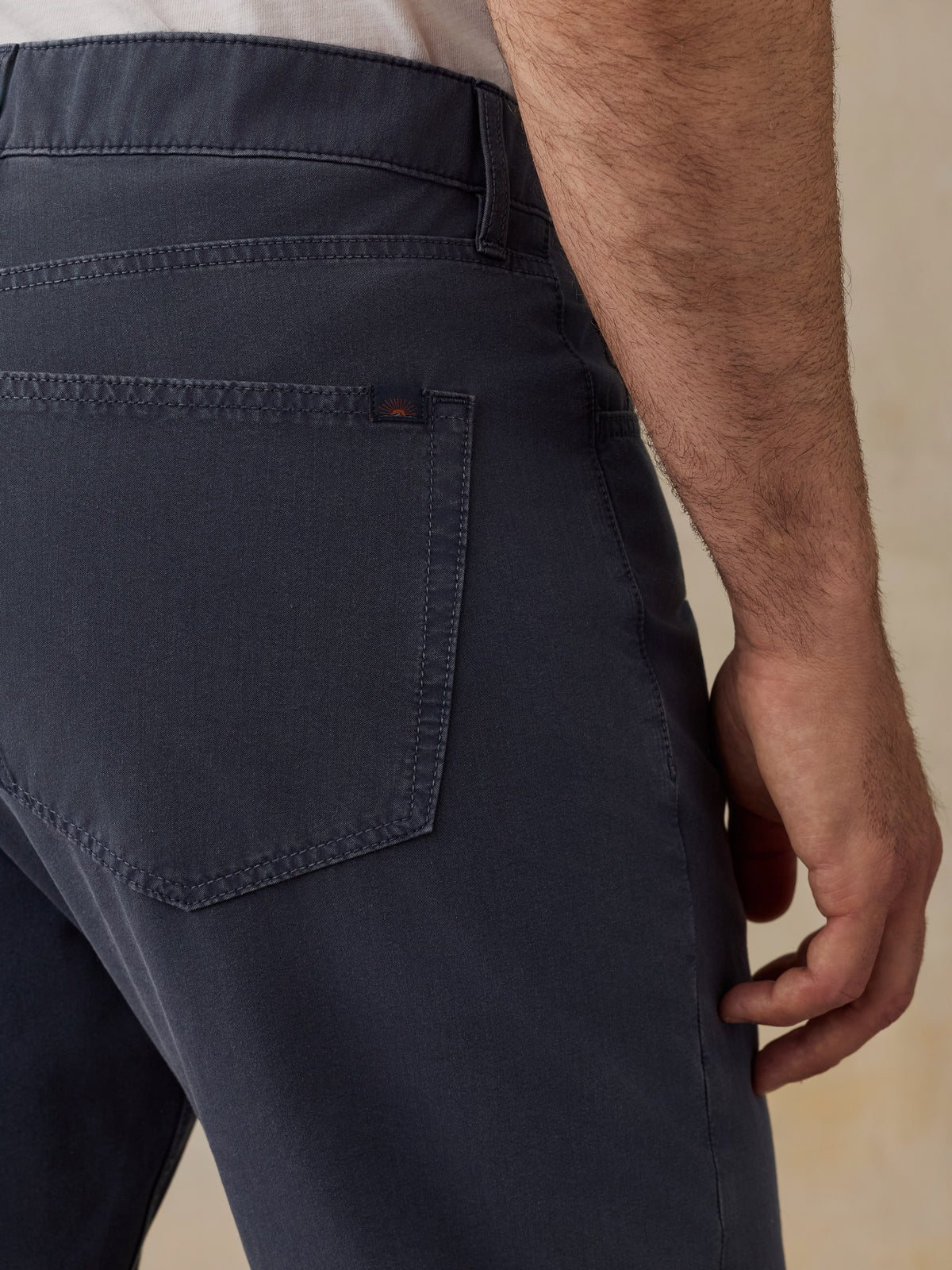 Close-up of a man wearing dark navy blue trousers, showing the back pocket and waistband area., image 5 of 5