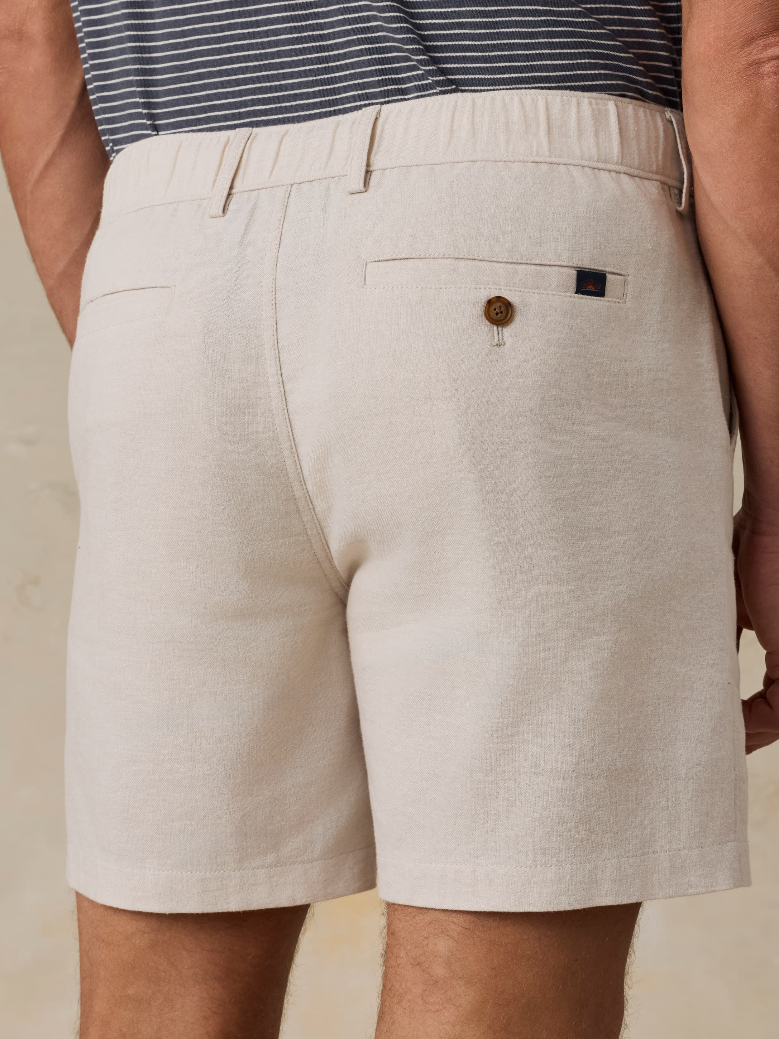 Beige shorts worn by a man on a neutral background
