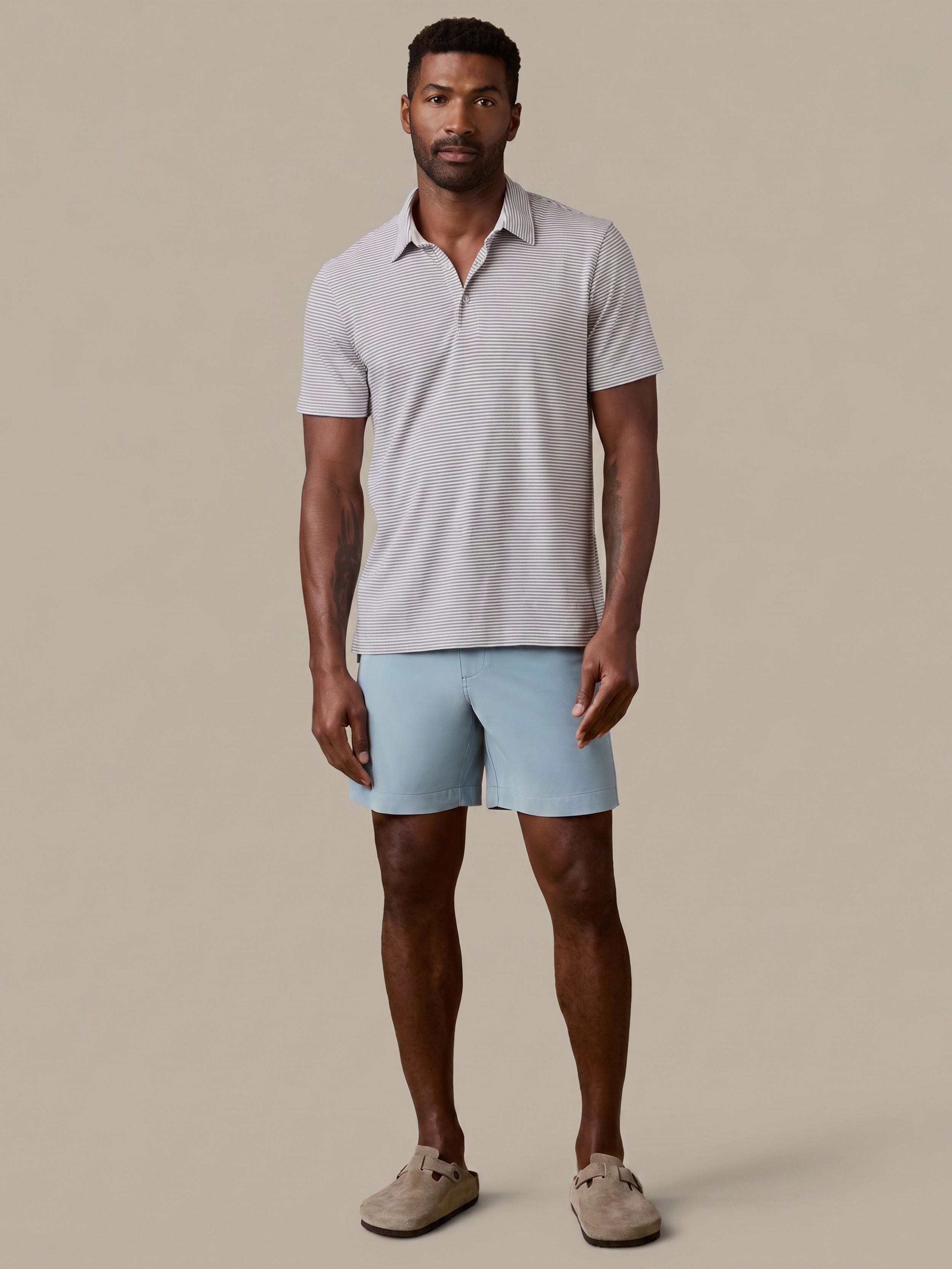 Man wearing a light gray polo shirt and light blue shorts on a beige background