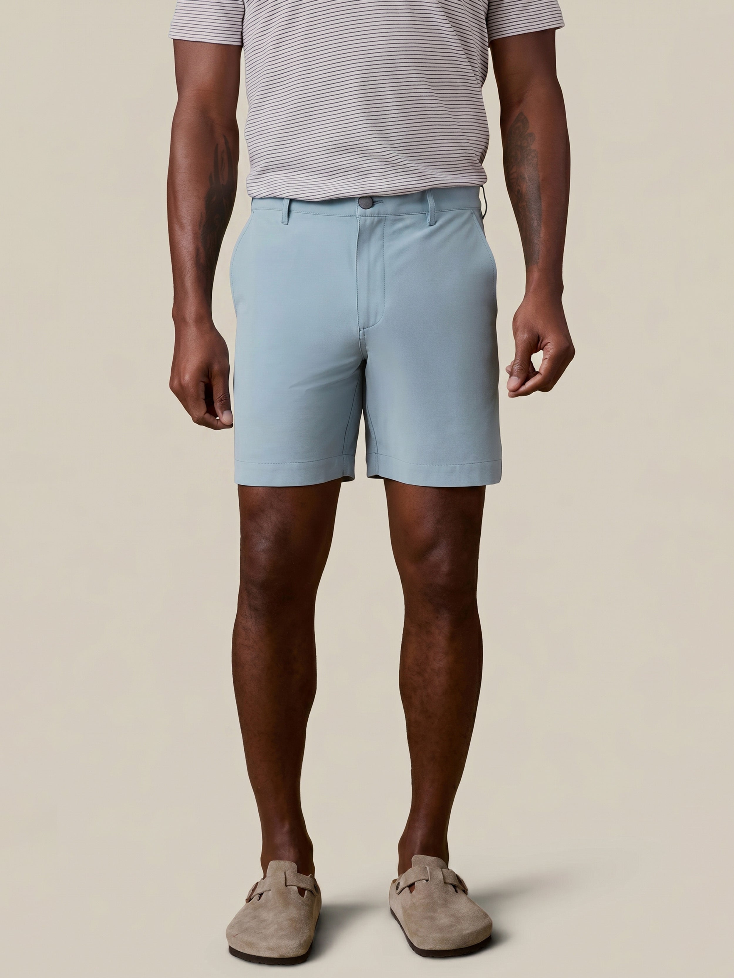 Man wearing light blue shorts and a striped shirt on a beige background