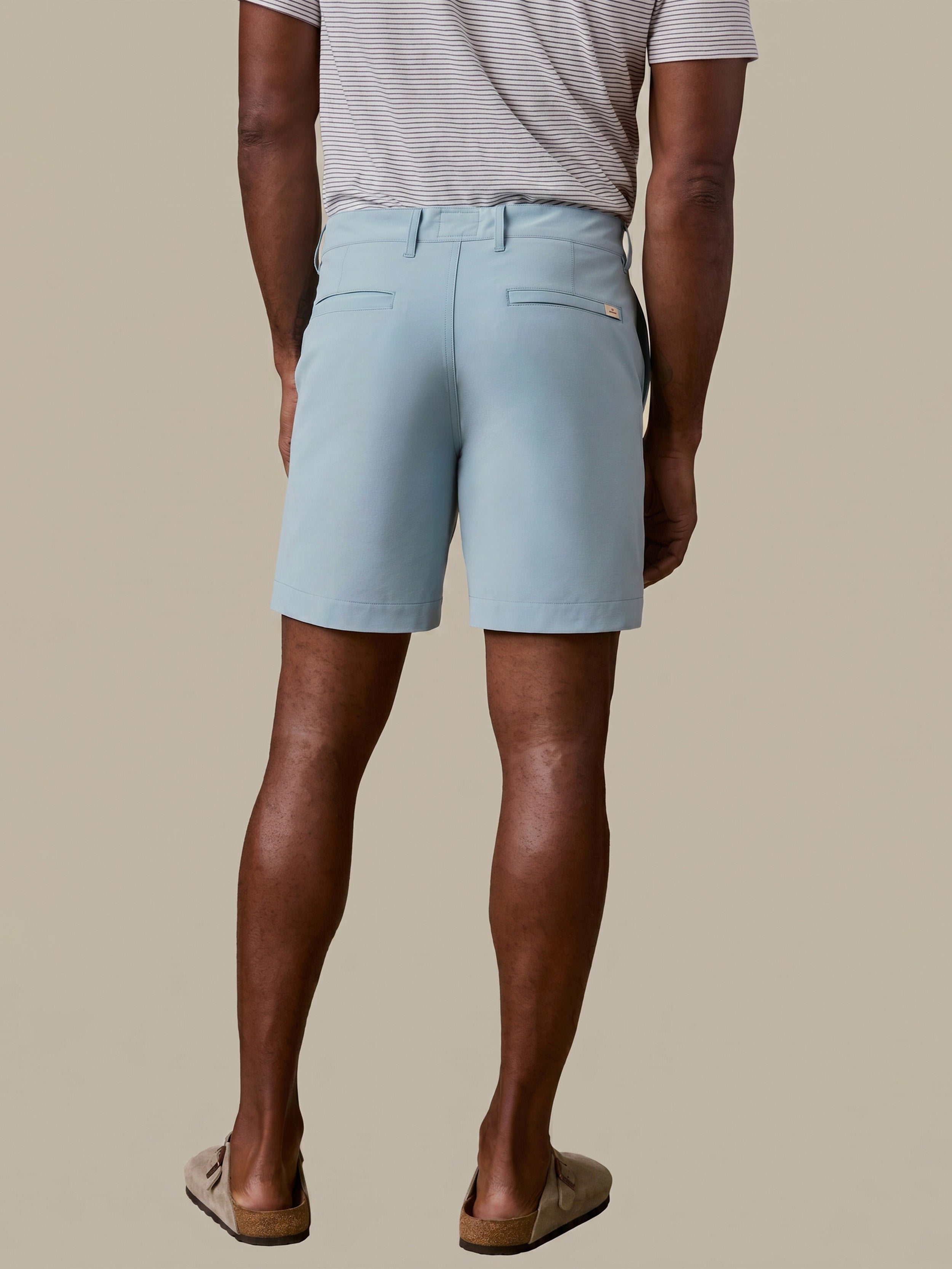 Man wearing light blue shorts on a beige background