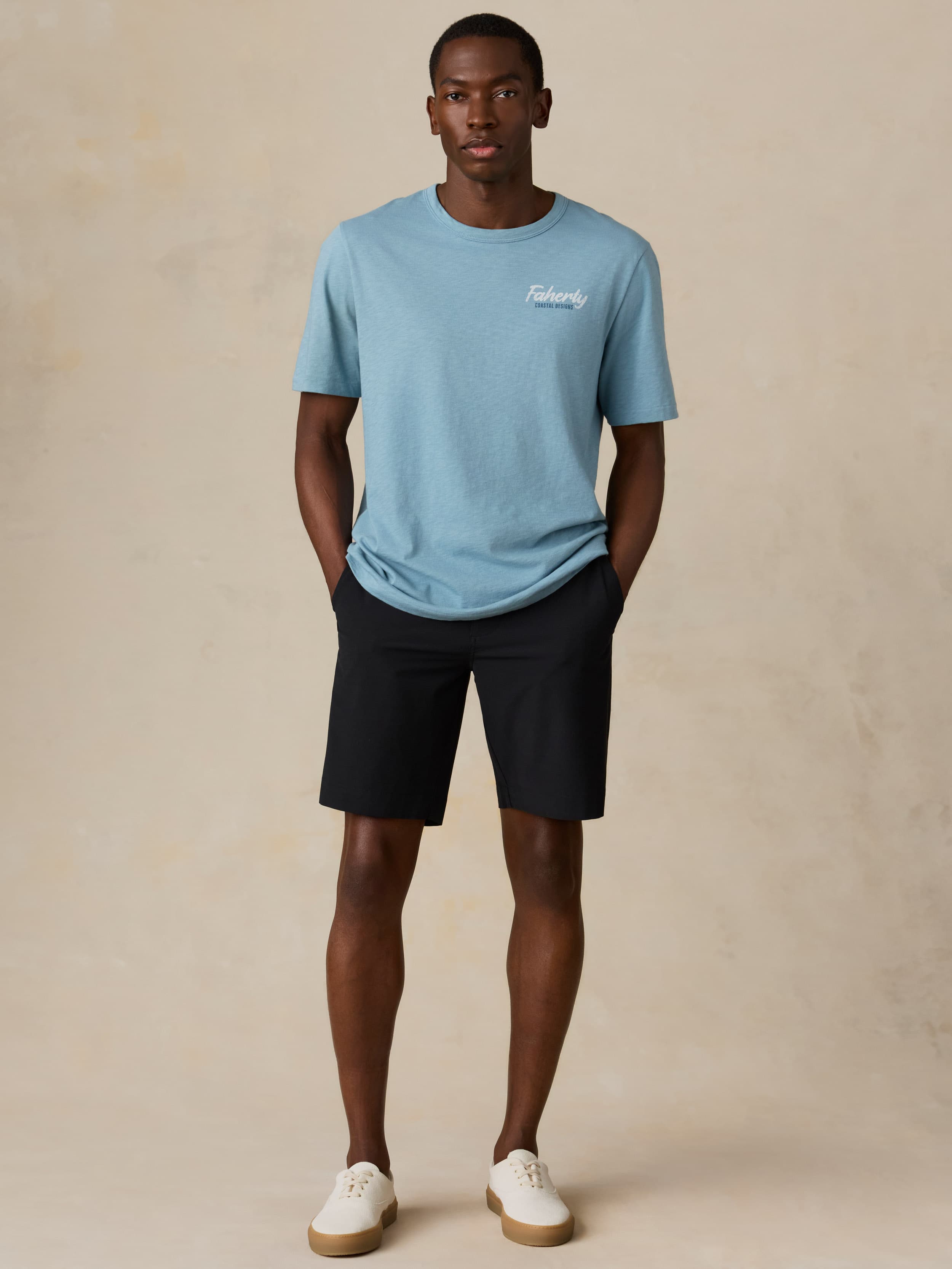 Man wearing a light blue t-shirt and black shorts on a beige background
