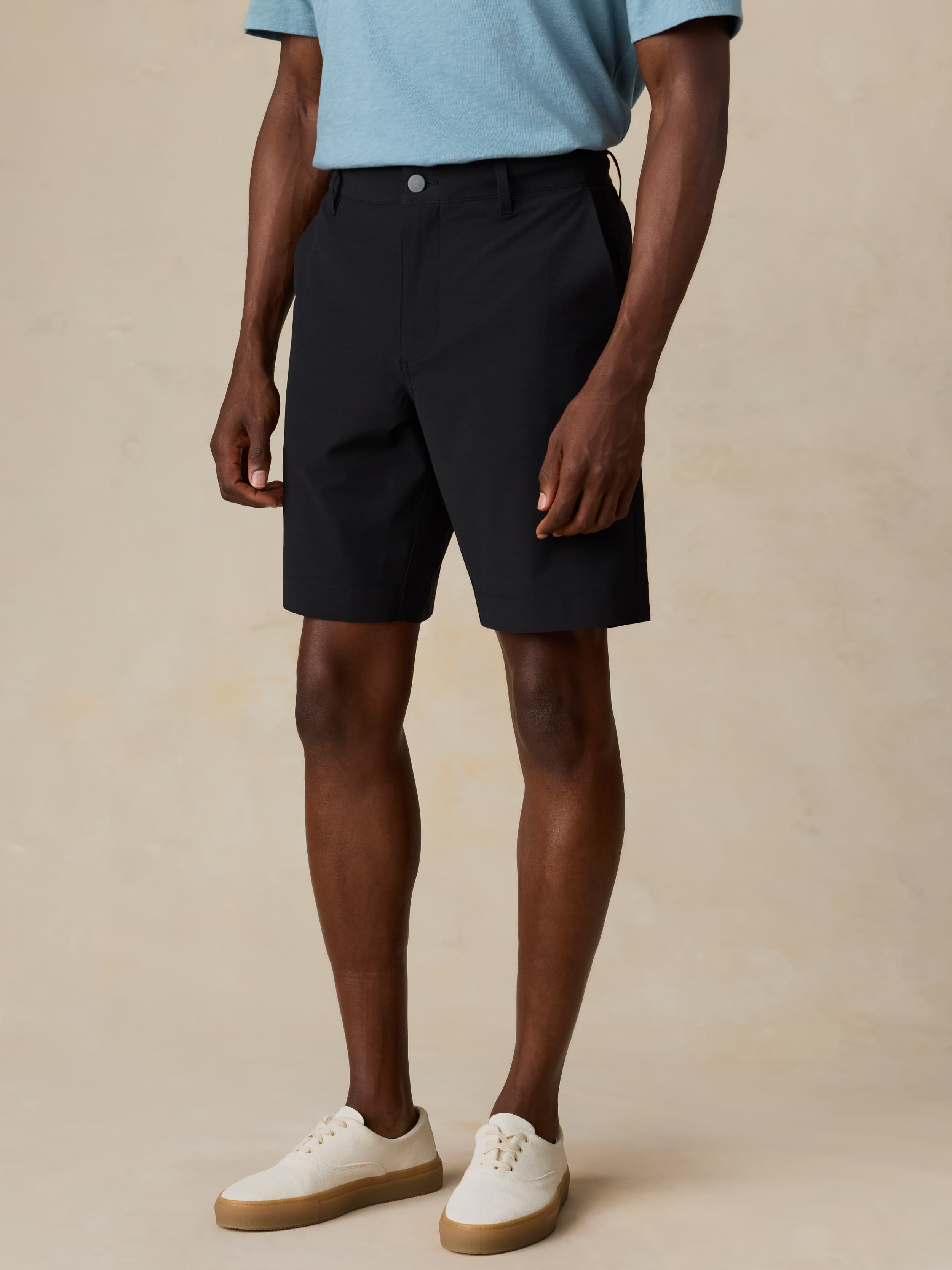 Man wearing black shorts and a light blue shirt on a beige background
