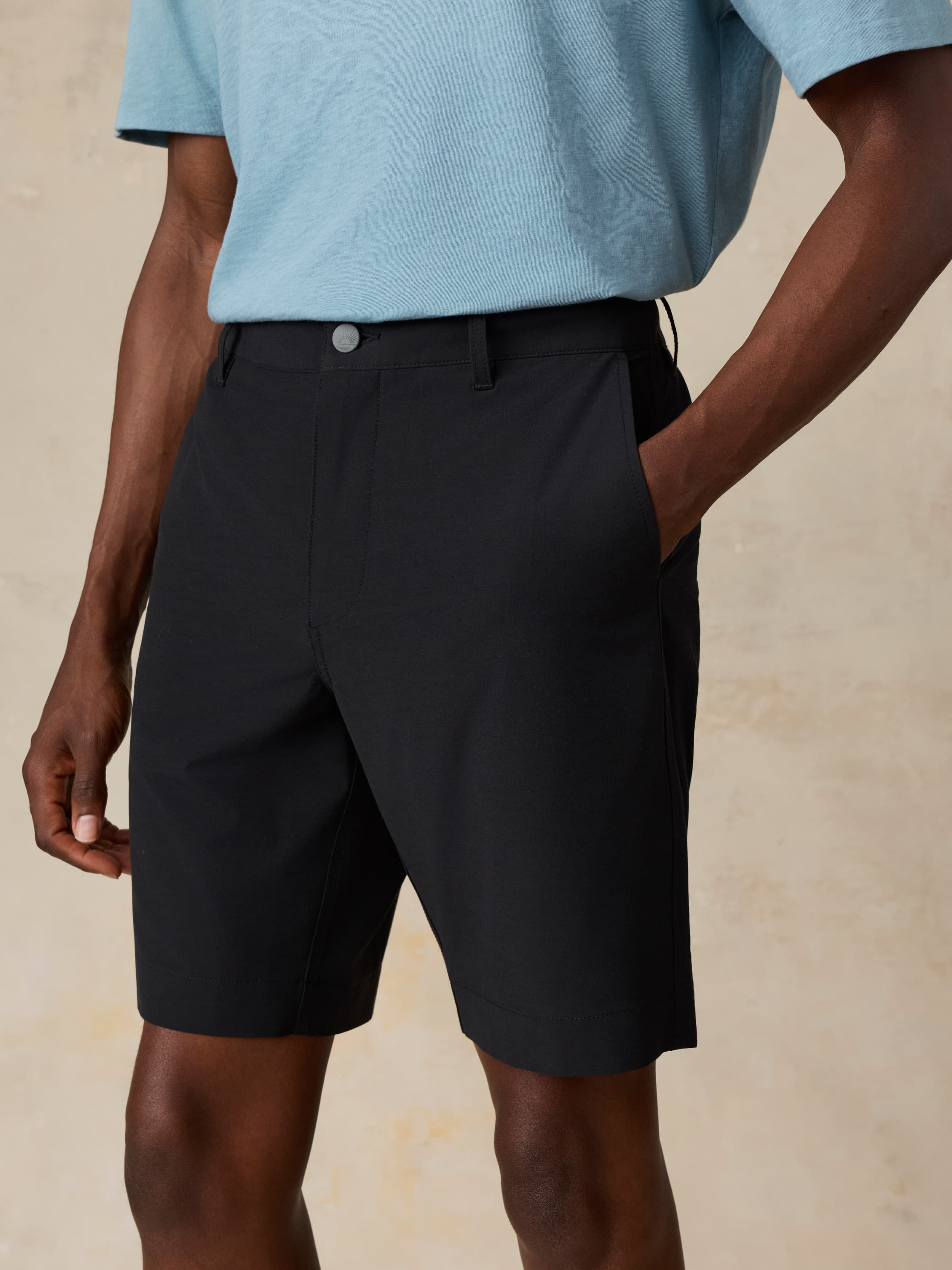 Man wearing black shorts and a light blue shirt on a beige background