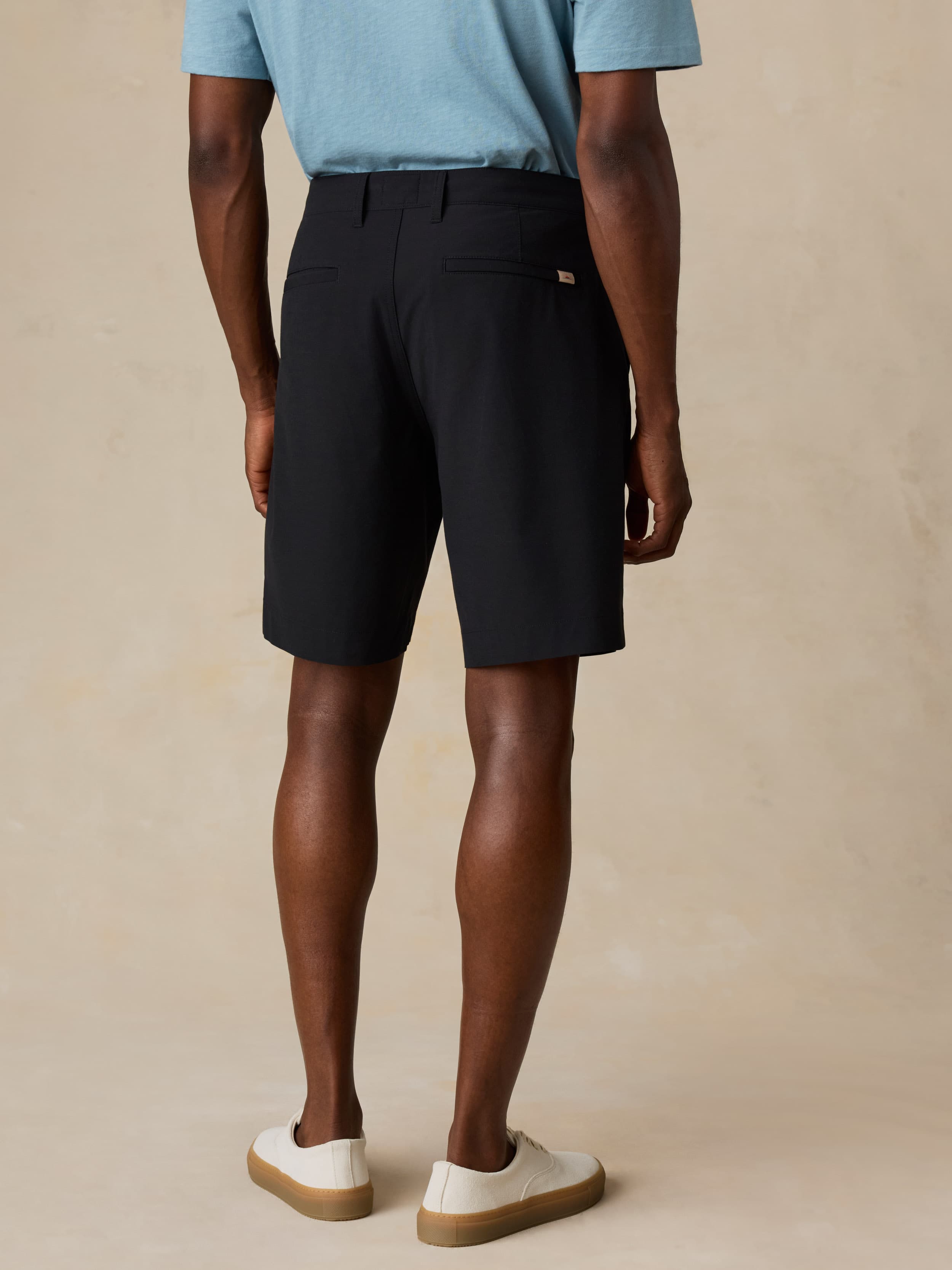 Man wearing black shorts and a light blue shirt on a beige background