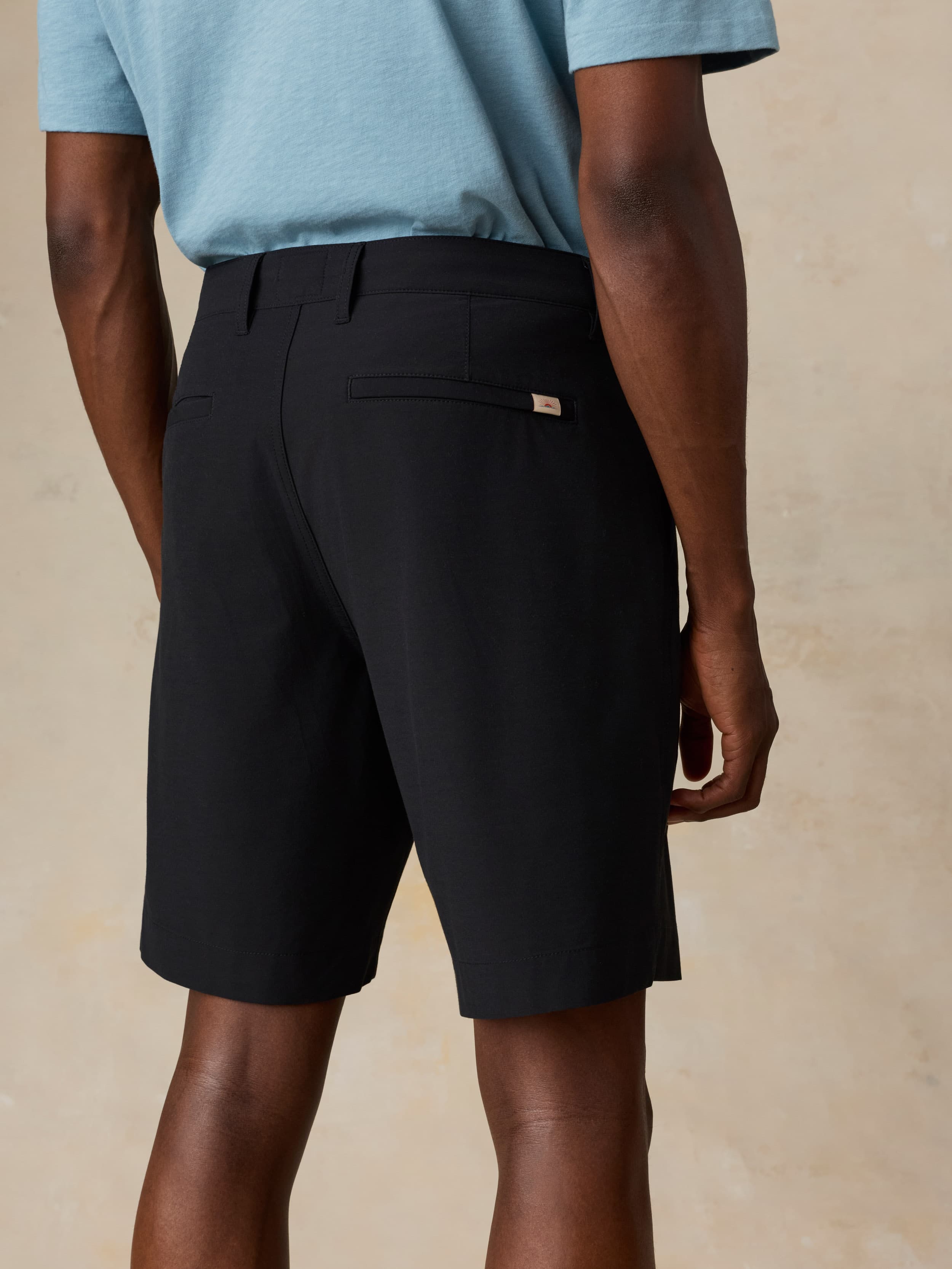 Man wearing black shorts and a light blue shirt on a beige background