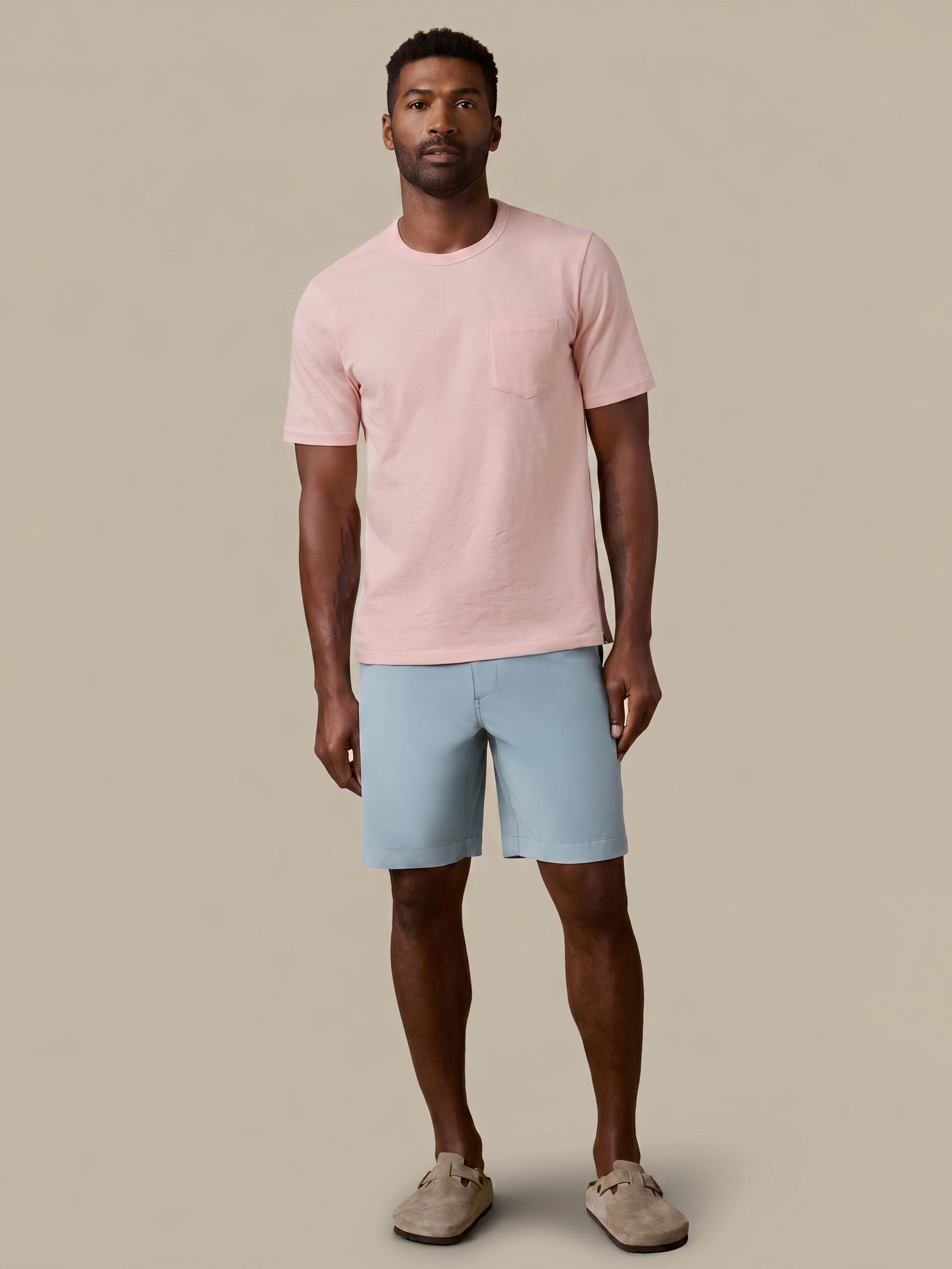 Man wearing a pink t-shirt and light blue shorts on a beige background