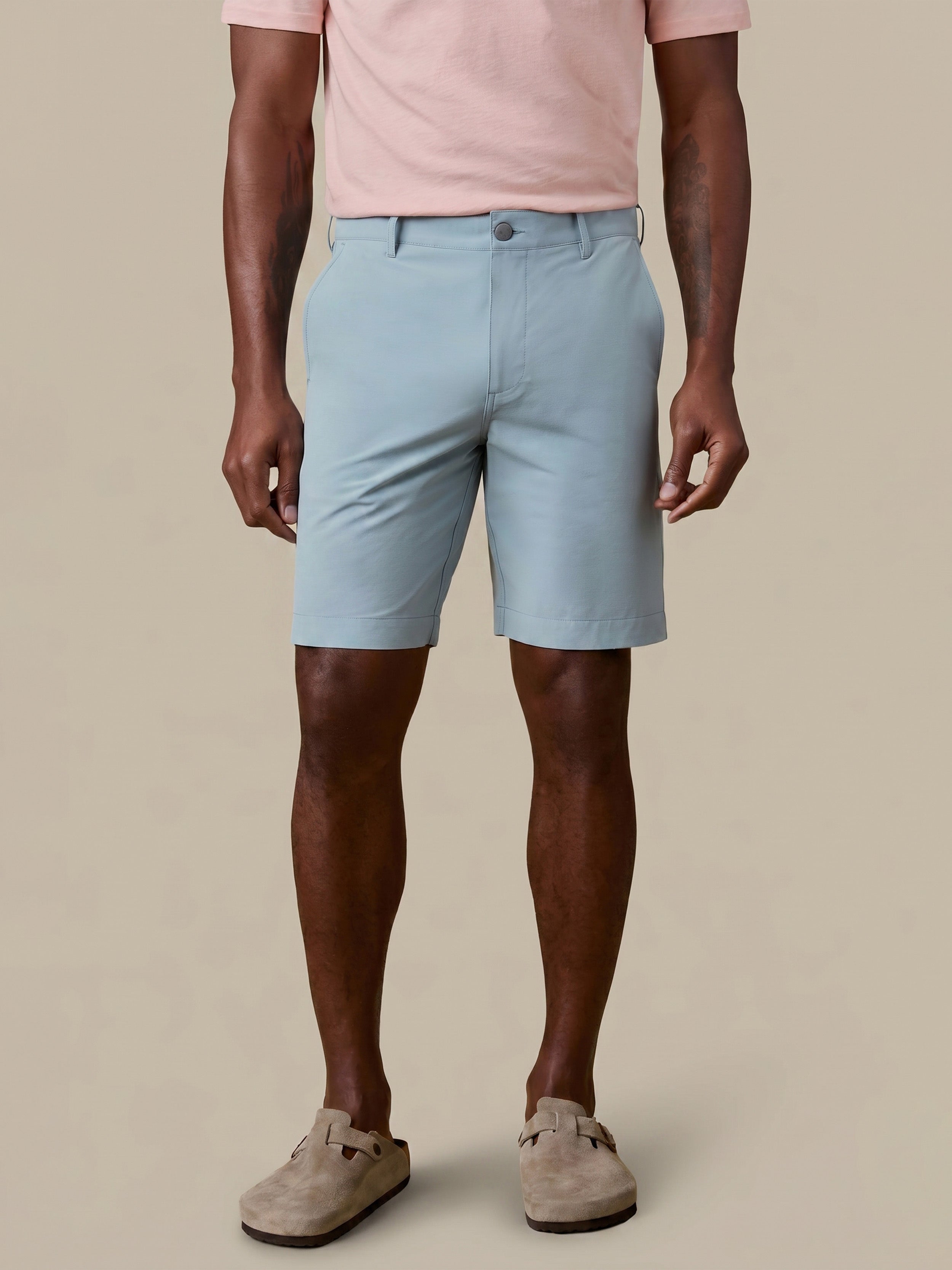 Man wearing light blue shorts and a pink shirt on a beige background