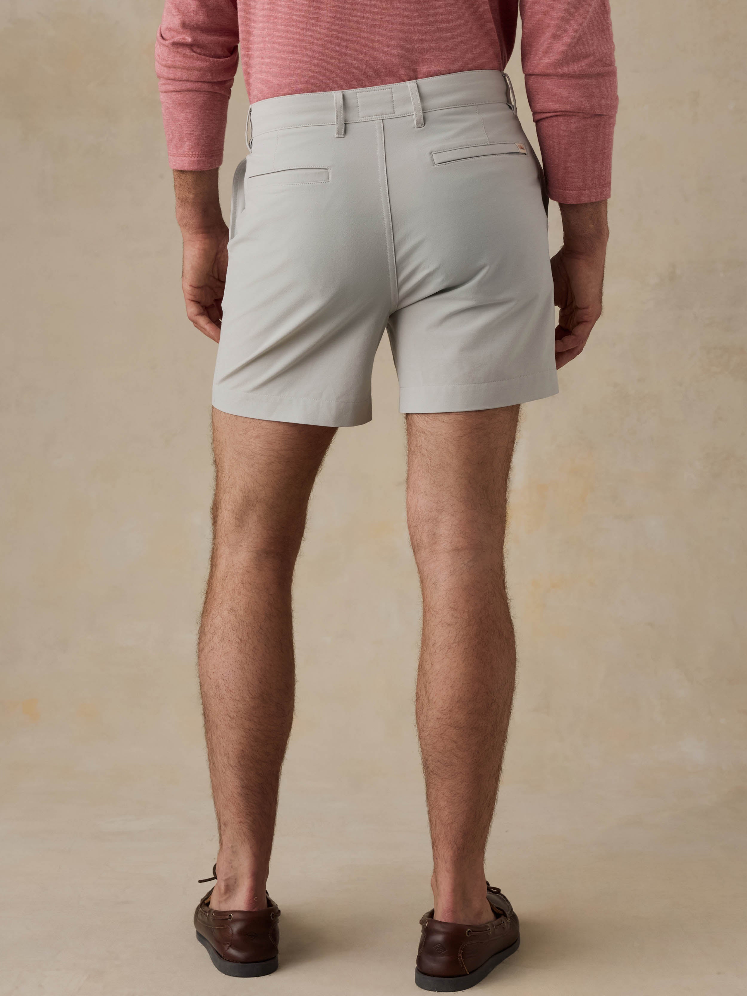 Man is wearing grey shorts and a red crewneck against a beige background