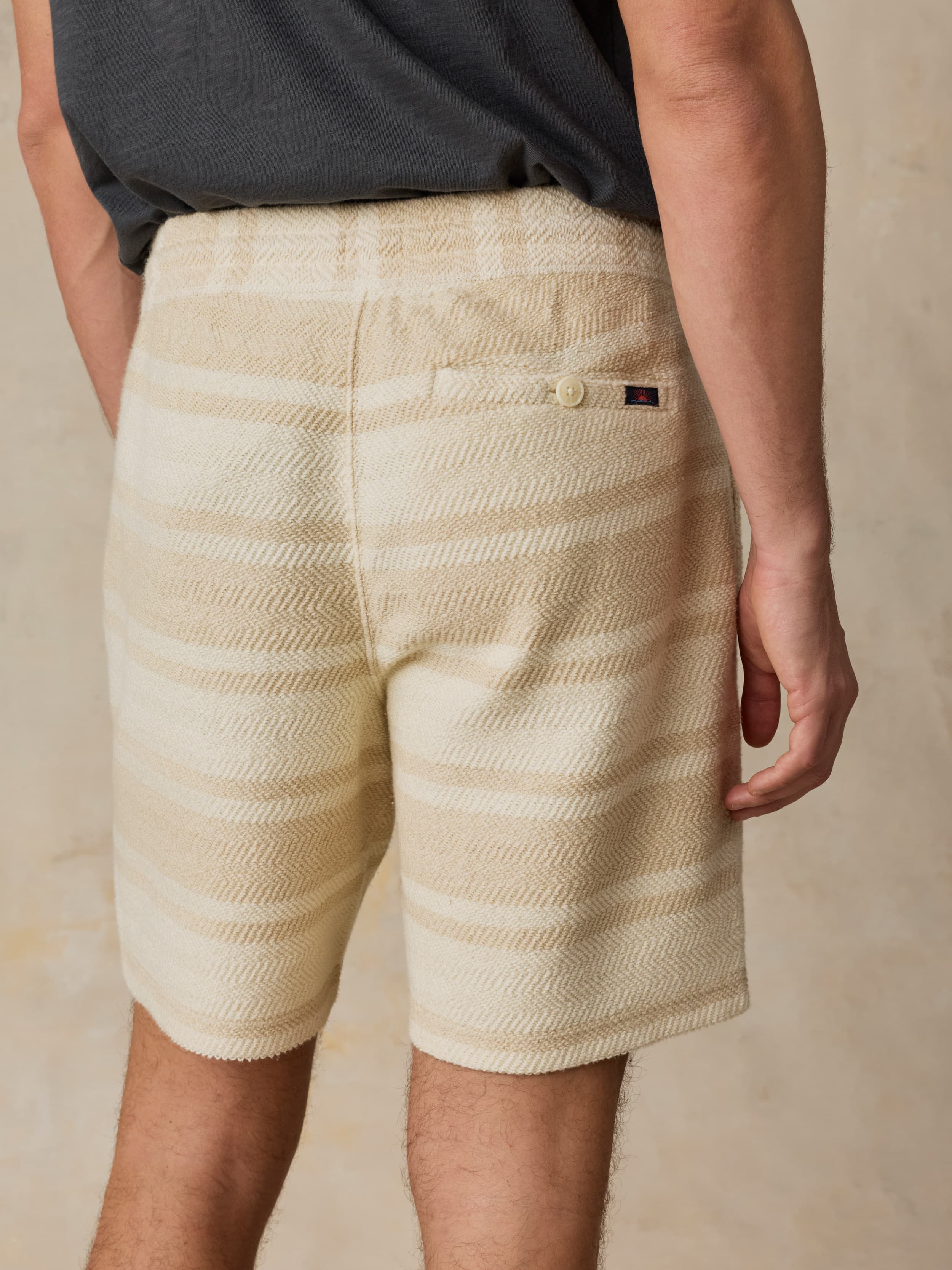 Man wearing beige striped shorts on a neutral background