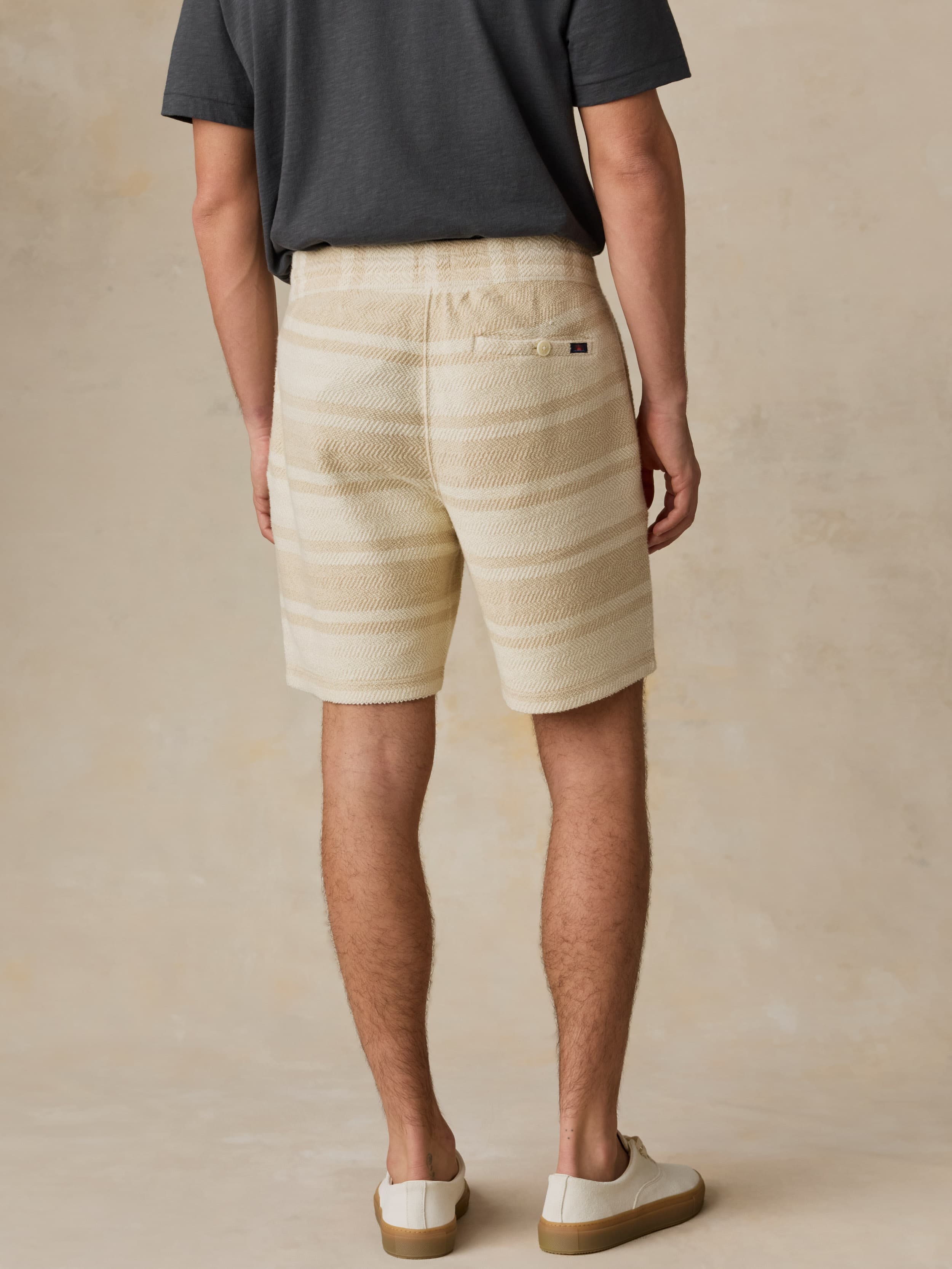 Man wearing beige shorts and a dark shirt on a beige background