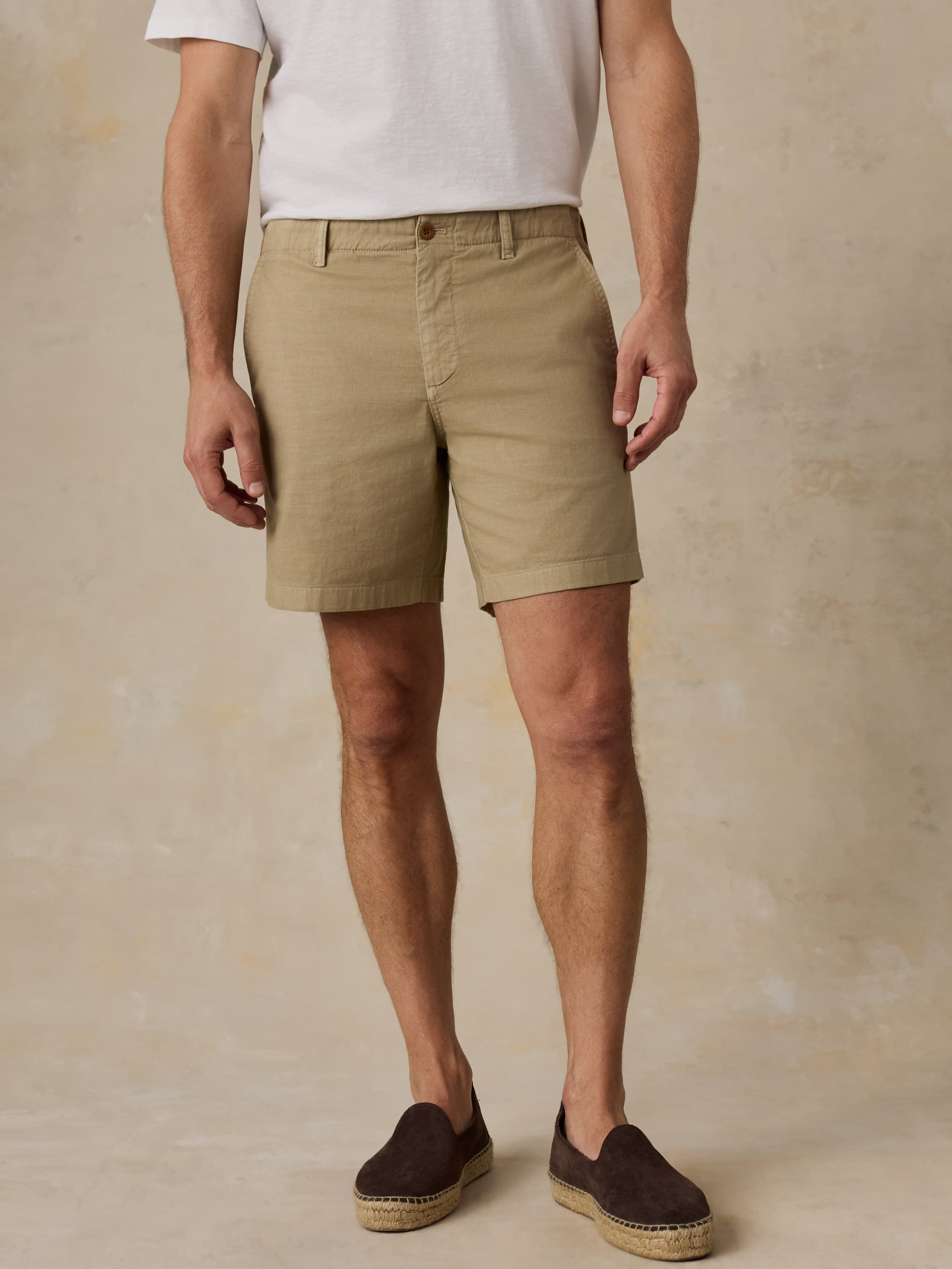 Man wearing beige shorts and brown shoes on a beige background