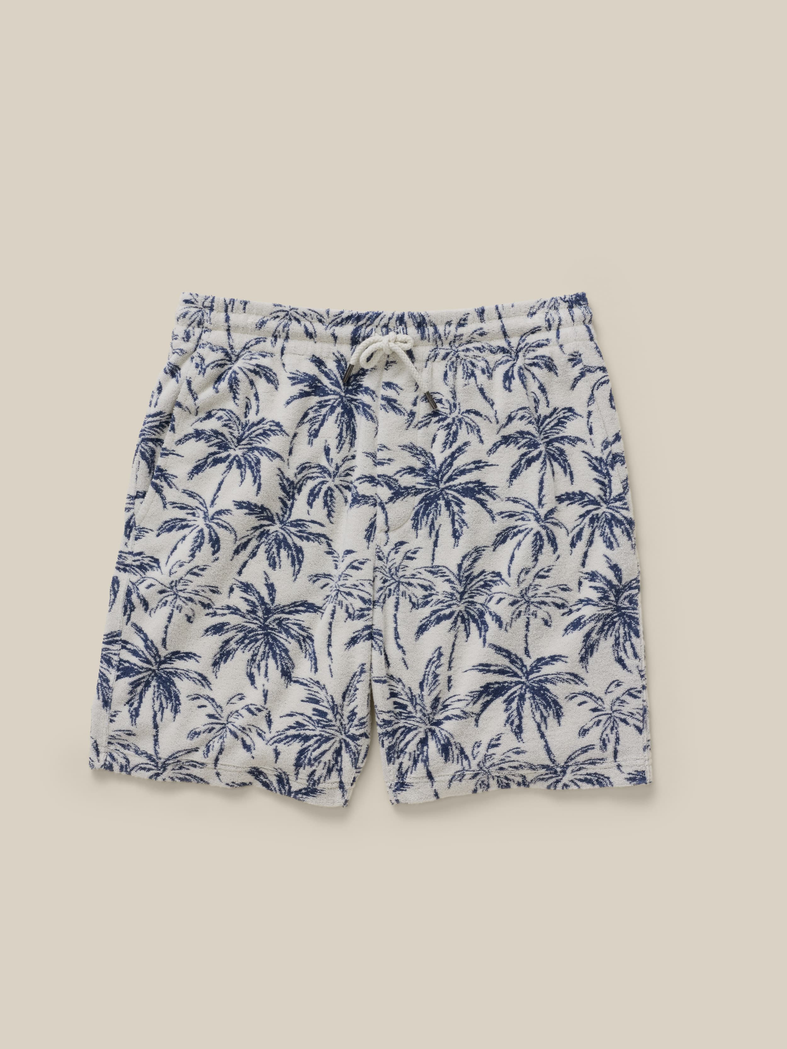 Blue palm tree patterned shorts on a beige background