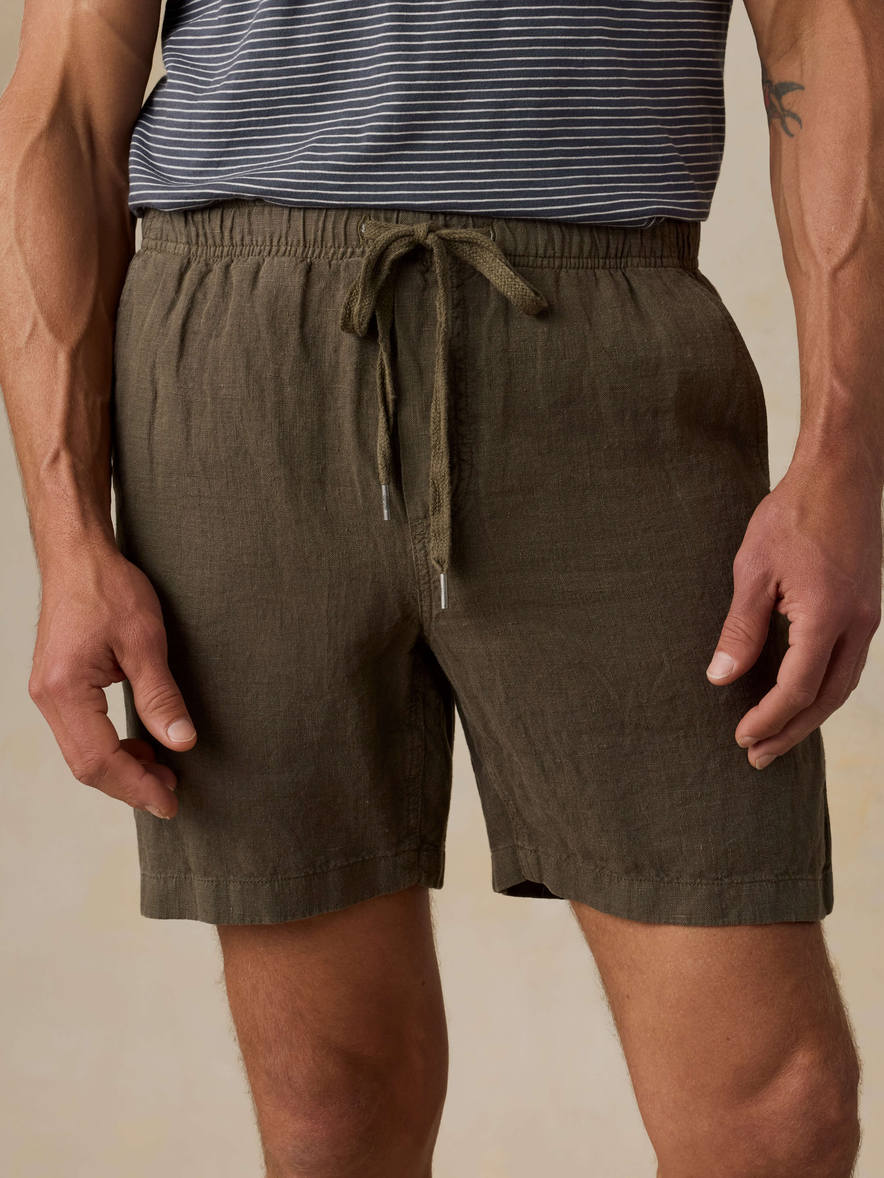 Man wearing green shorts and a striped shirt on a beige background