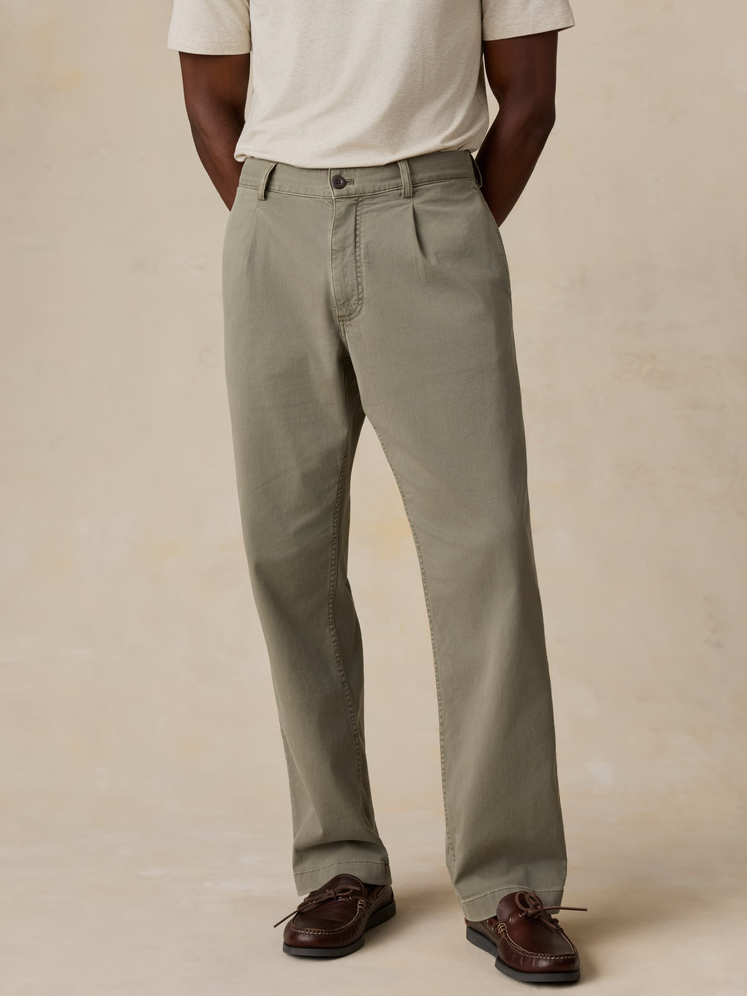 Man wearing green pants and a white shirt on a beige background