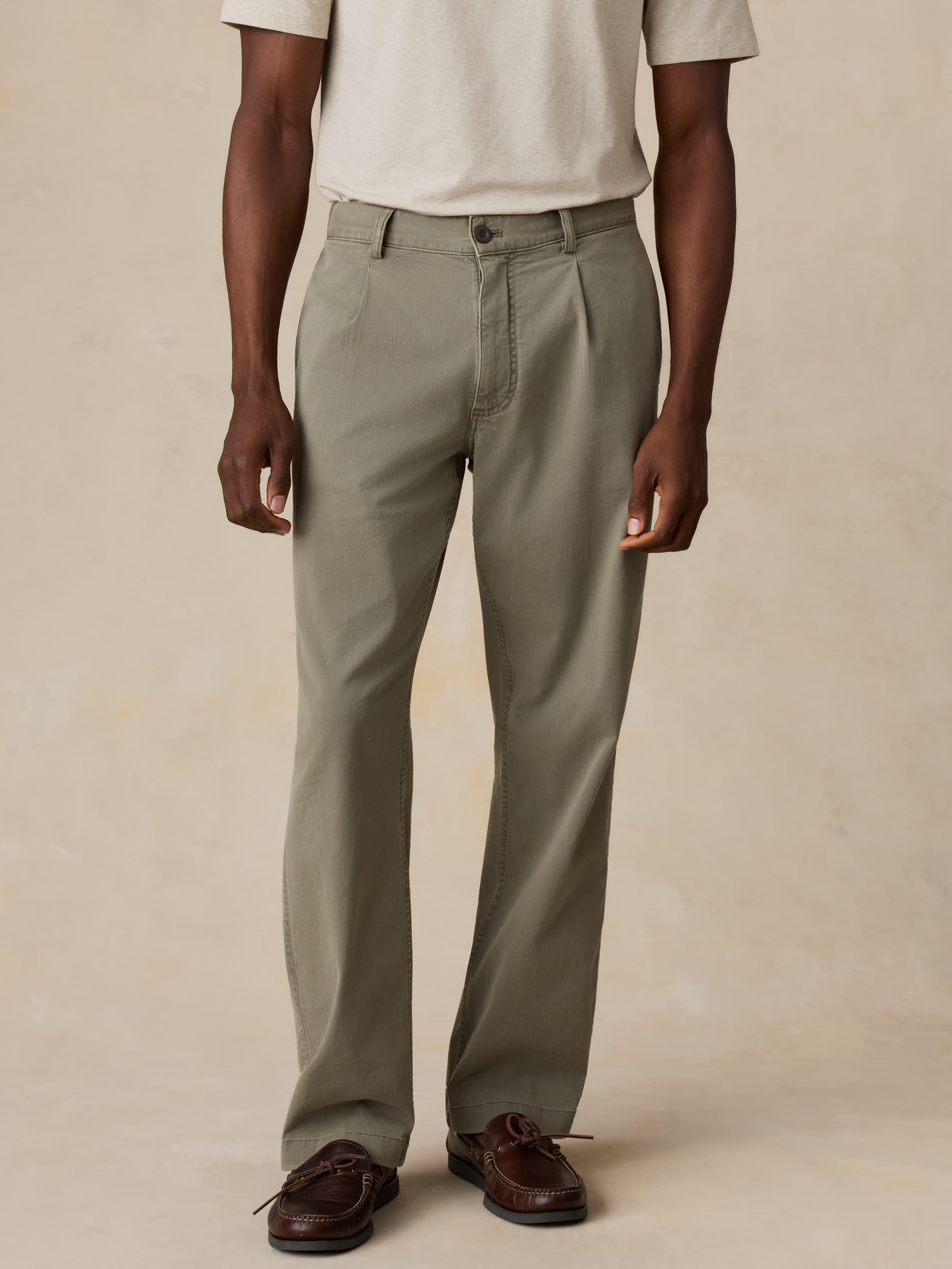 Man wearing green pants and a white shirt on a beige background