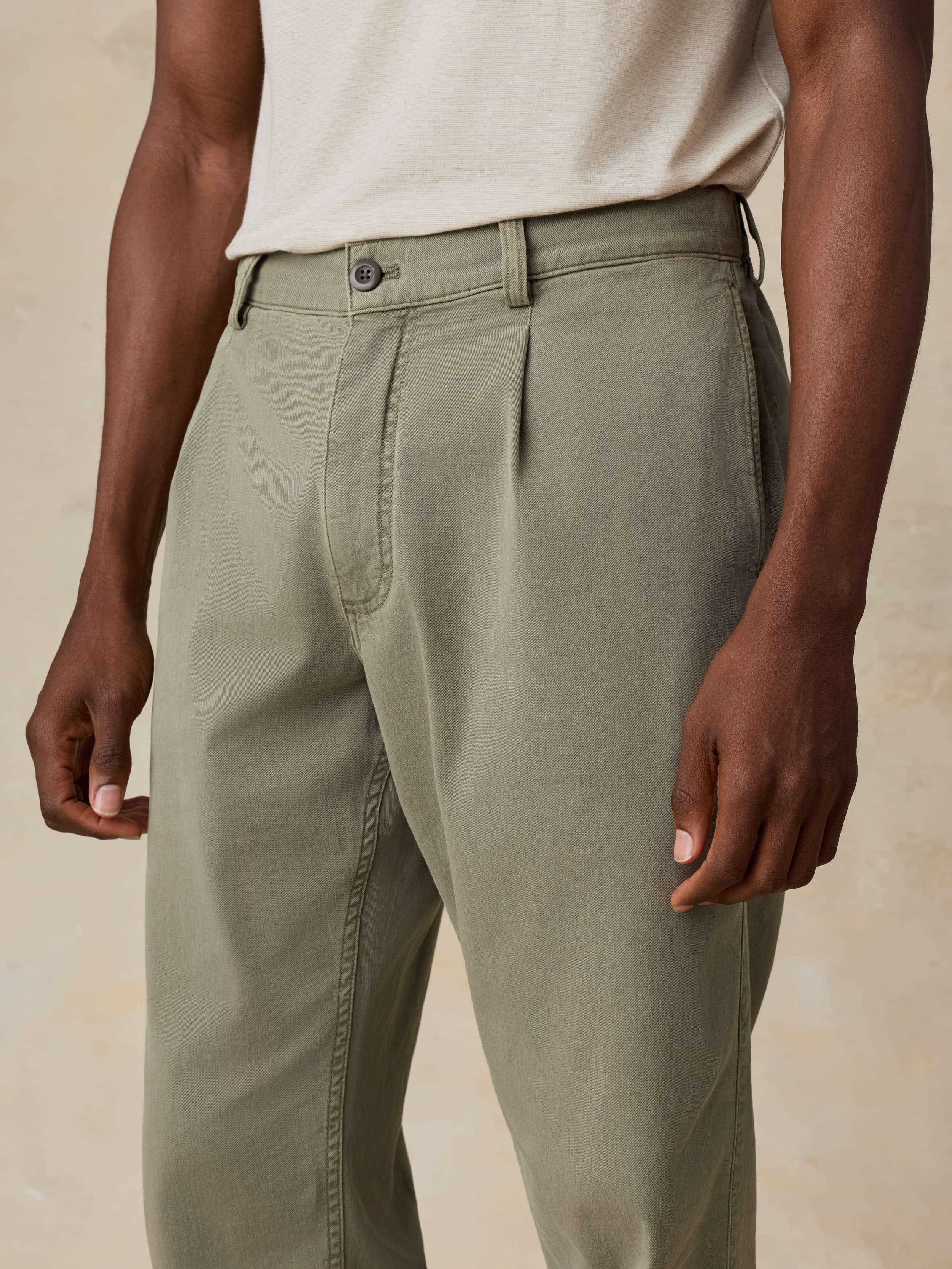 Man wearing green pants and a white shirt on a beige background