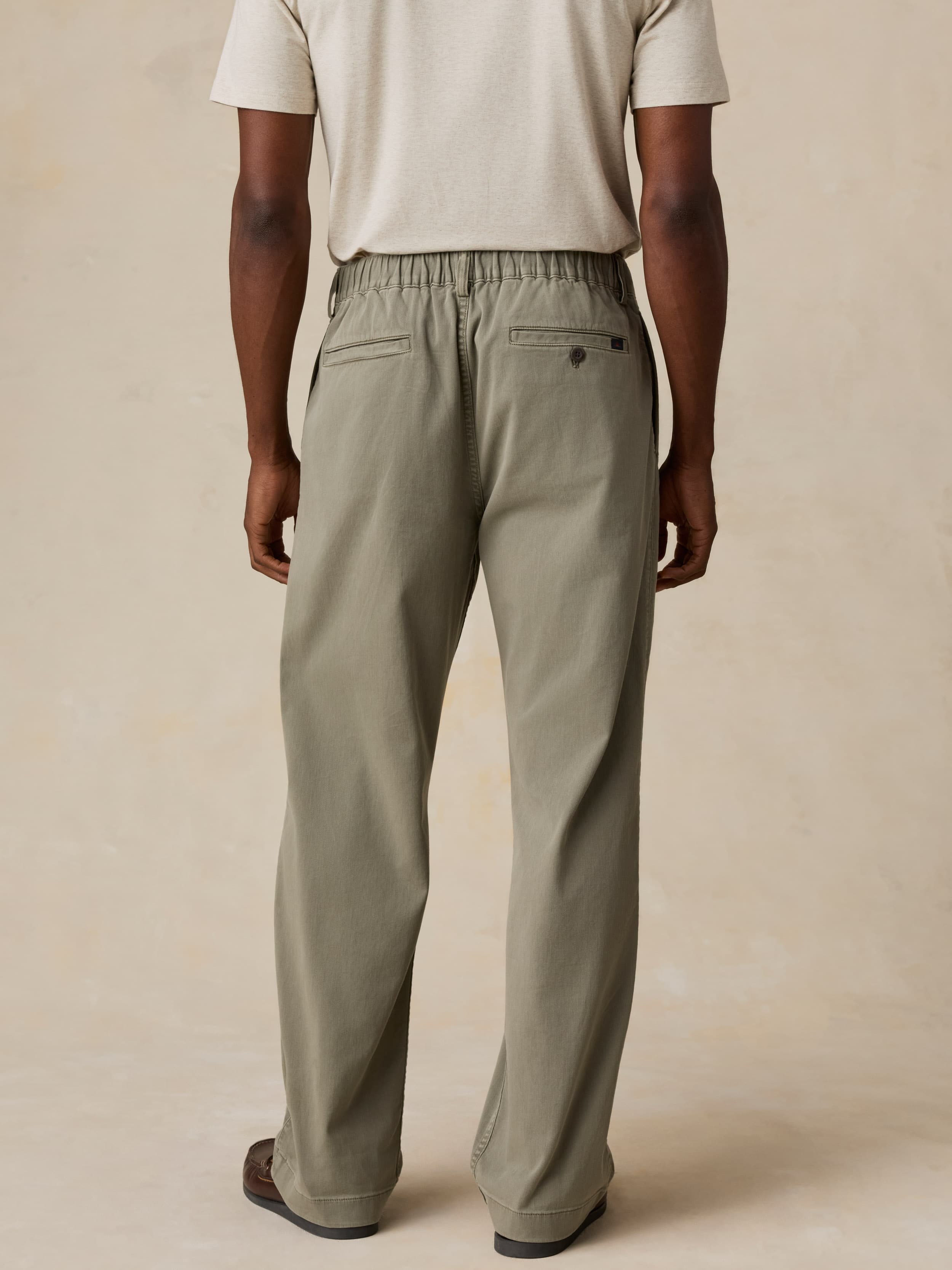 Man wearing green pants and a white shirt on a beige background