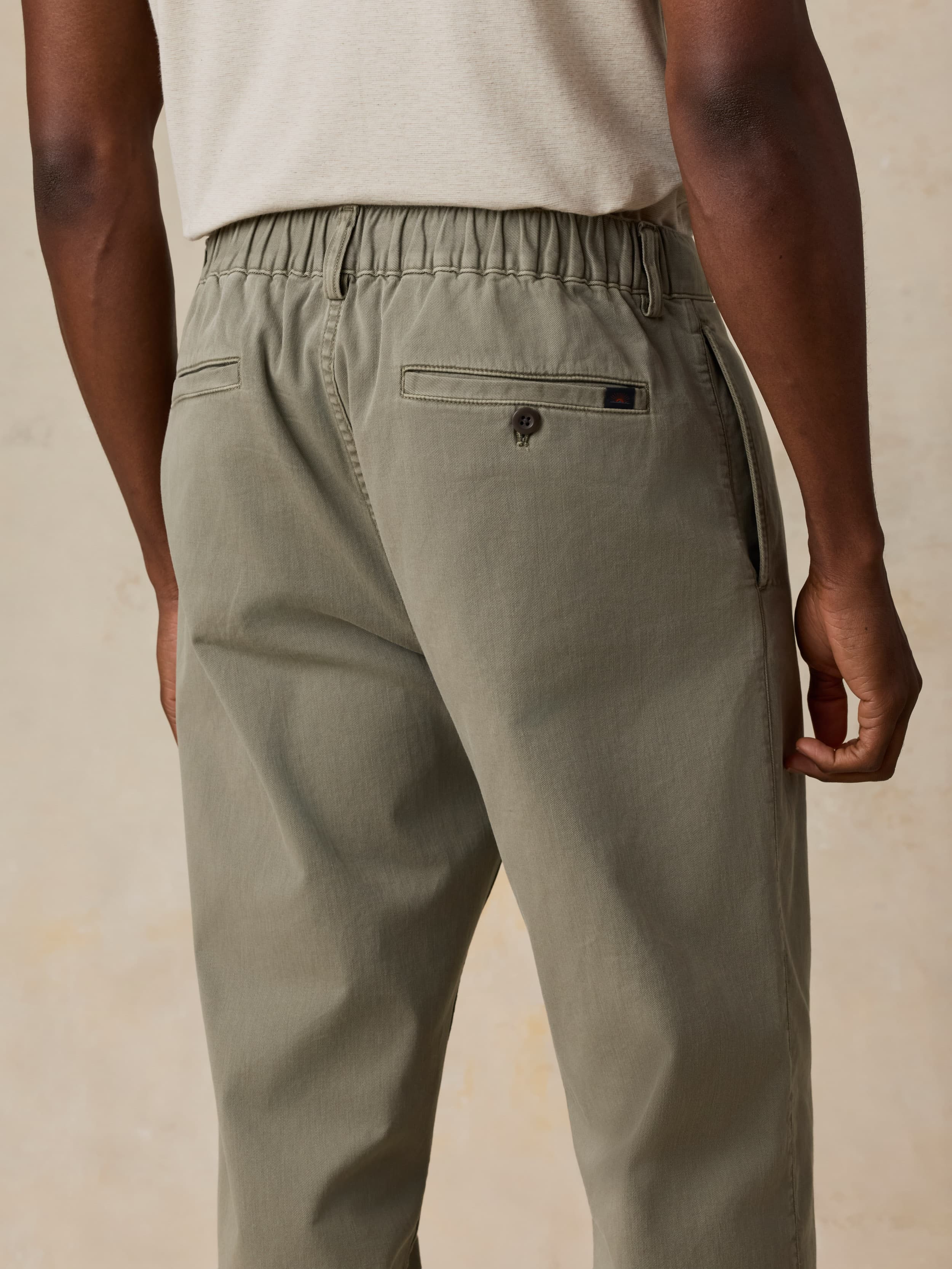 Man wearing green pants and a white shirt on a beige background
