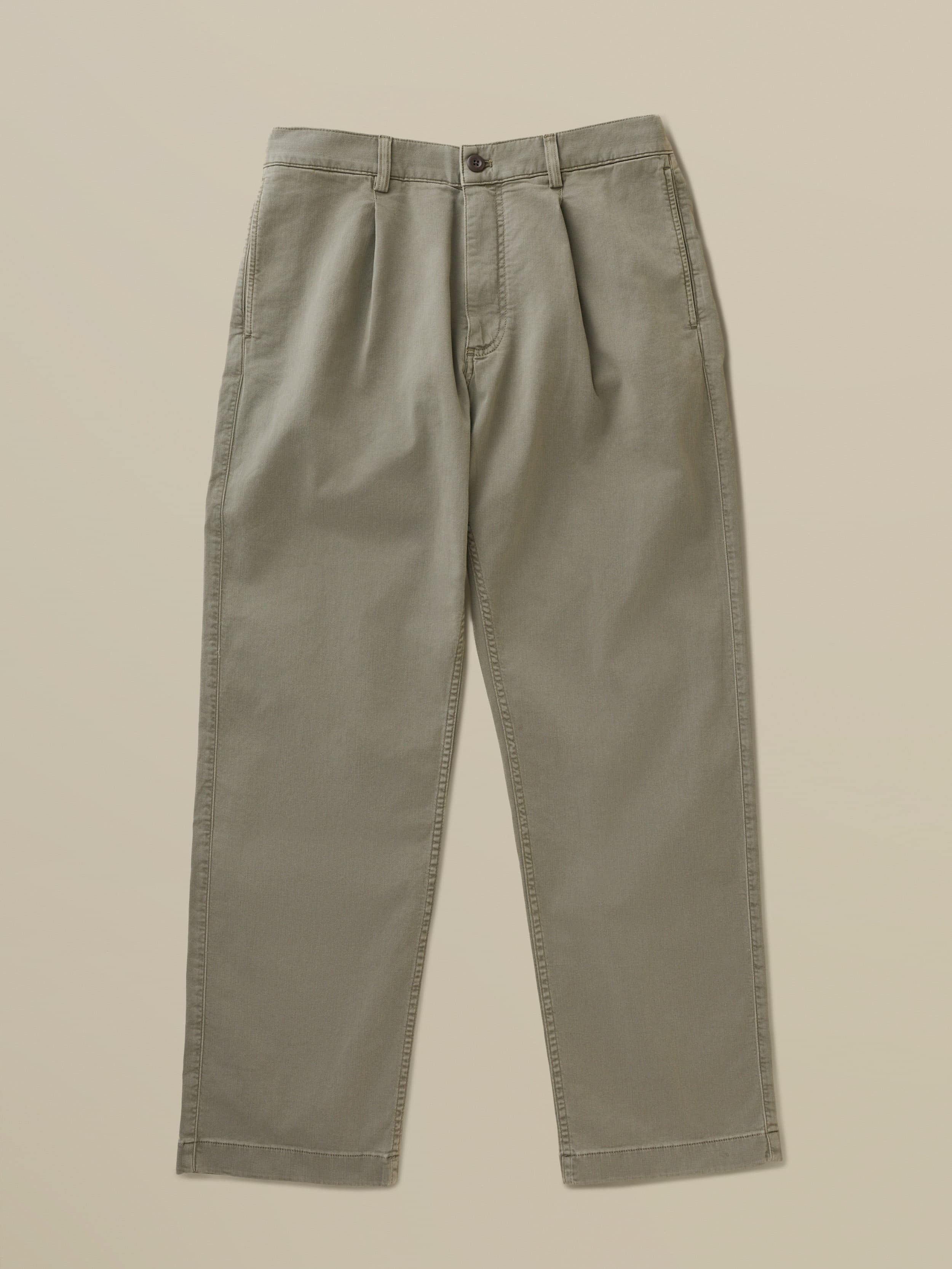Green chino pants against a beige background