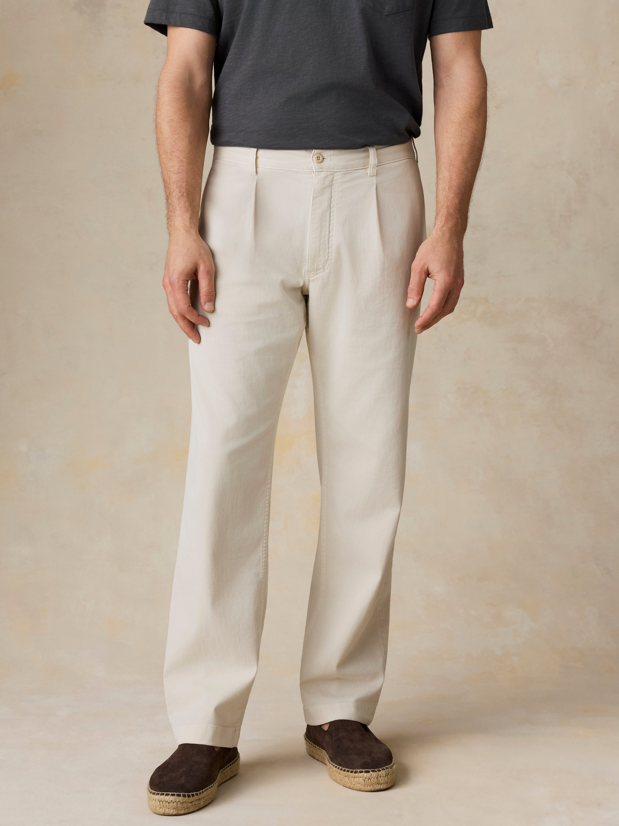 Man wearing beige pants and a dark shirt against a beige background