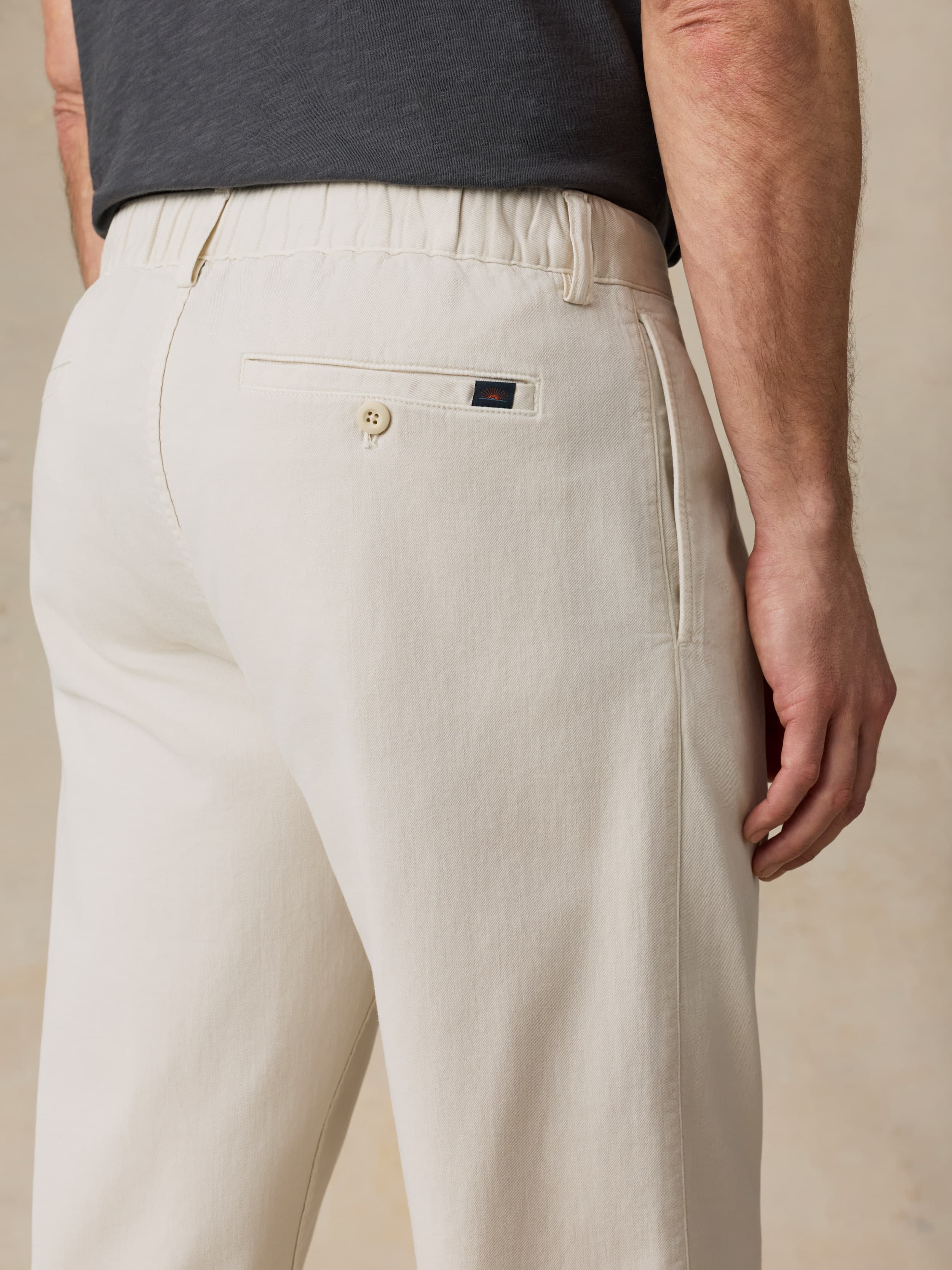 Man wearing beige pants and a dark shirt against a beige background