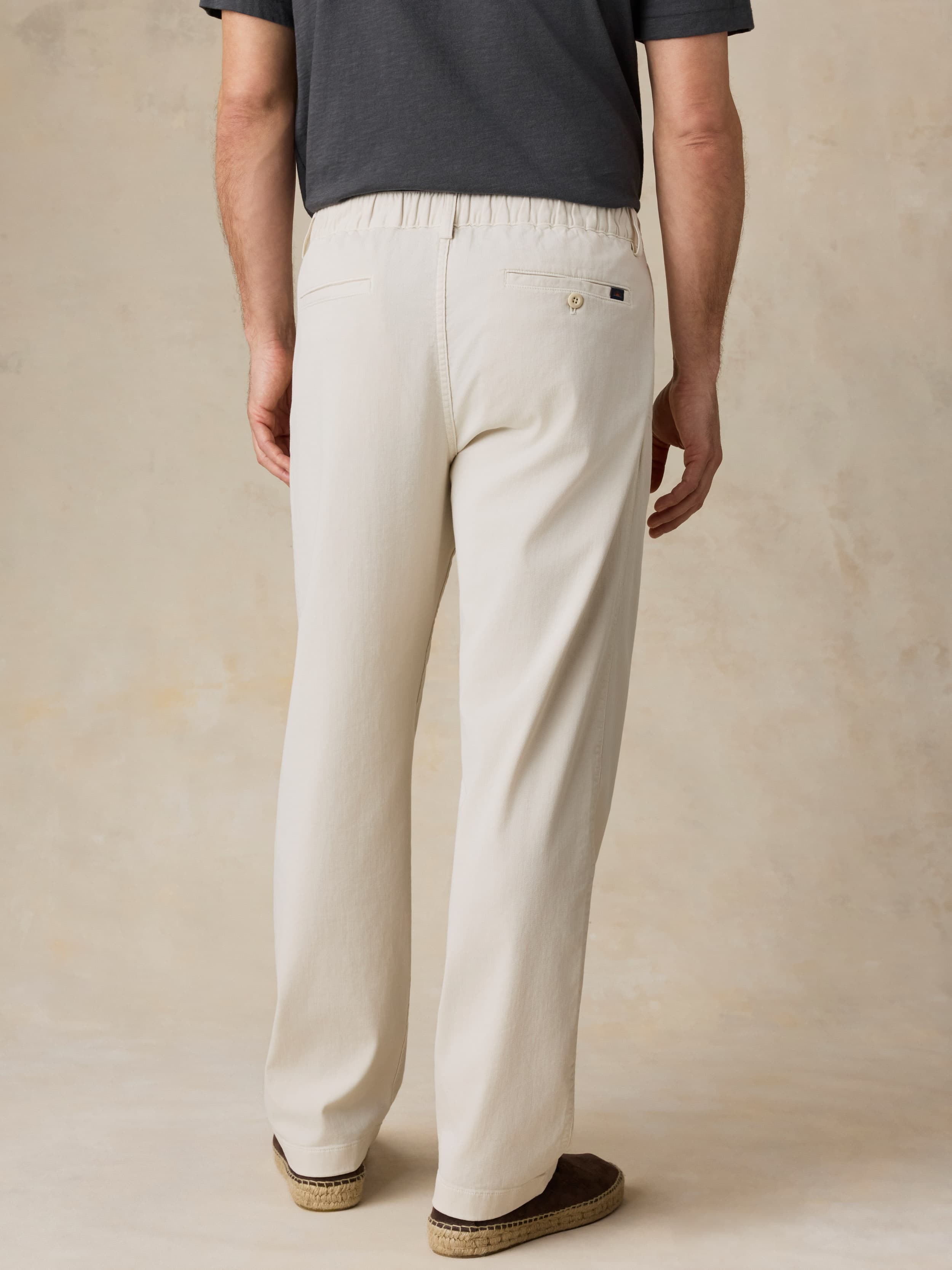 Man wearing beige pants and a dark shirt against a beige background