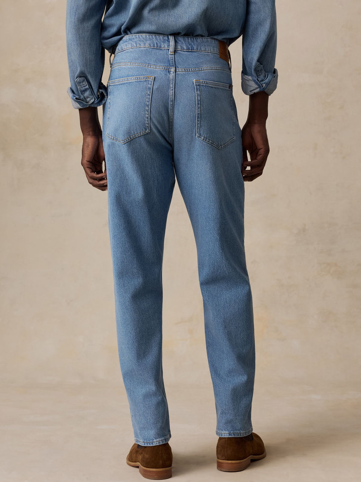 A man viewed from behind wearing a light blue denim shirt and matching light blue jeans, image 3 of 5