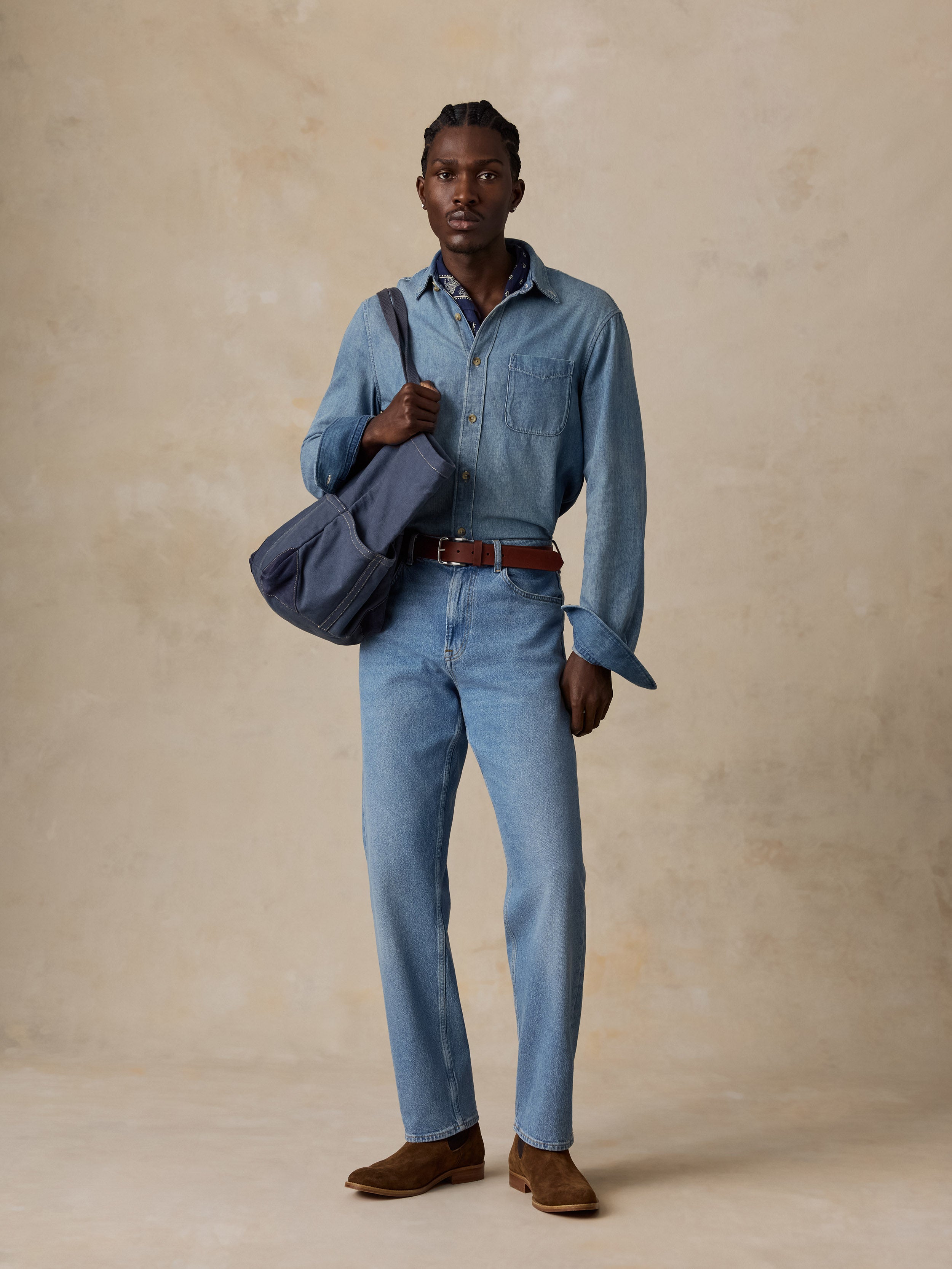 A man wearing a light blue denim shirt and matching light blue jeans