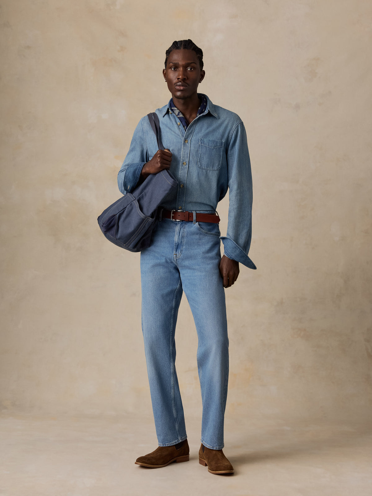 A man wearing a light blue denim shirt and matching light blue jeans, image 1 of 5