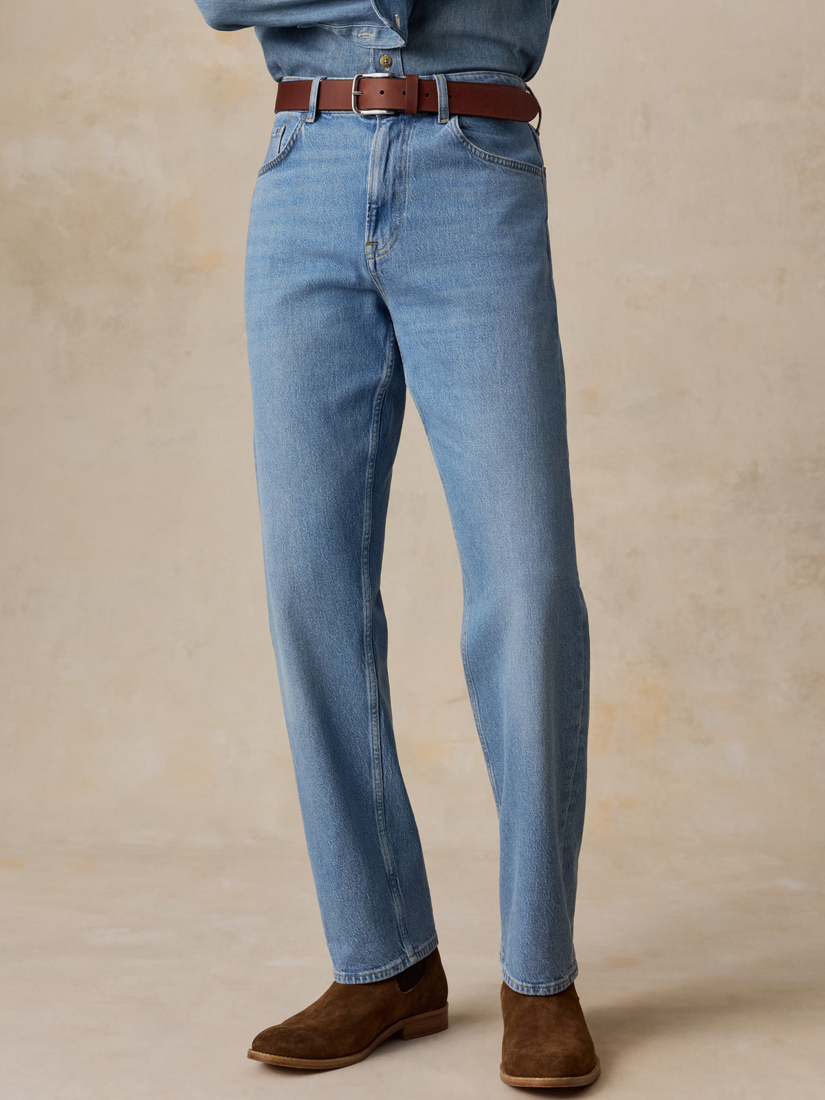 A man wearing a light blue denim shirt and matching light blue jeans, image 2 of 5