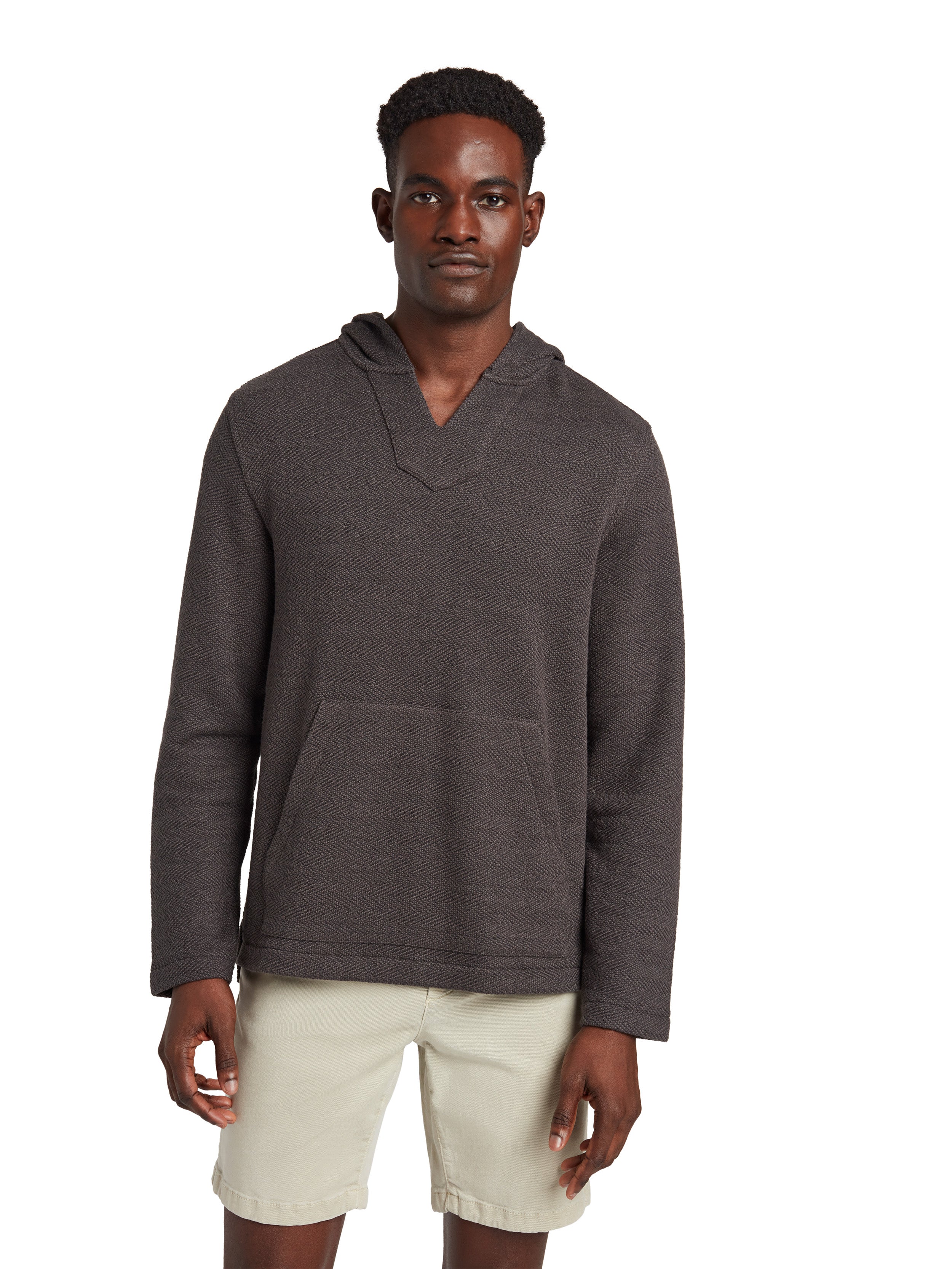 A man wearing a black hoodie and beige shorts