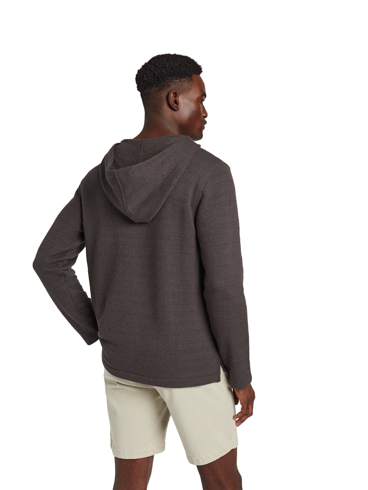 A man viewed from behind wearing a black hoodie and beige shorts, image 3 of 3