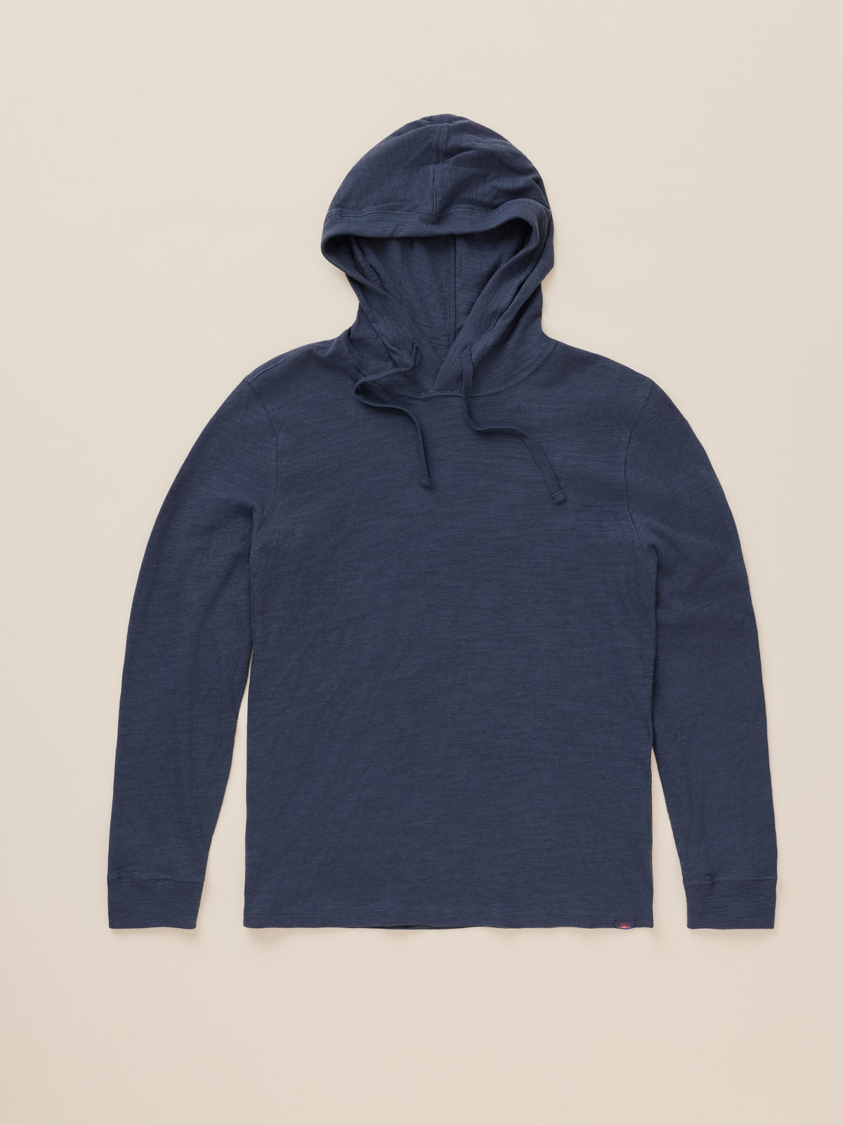 A navy blue long-sleeve hooded shirt with drawstrings, laid flat against a light beige background., image 7 of 8