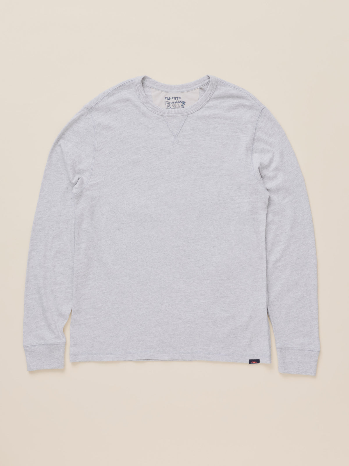 A light gray heather long-sleeve crewneck shirt by Faherty, laid flat against a solid beige background., image 7 of 8