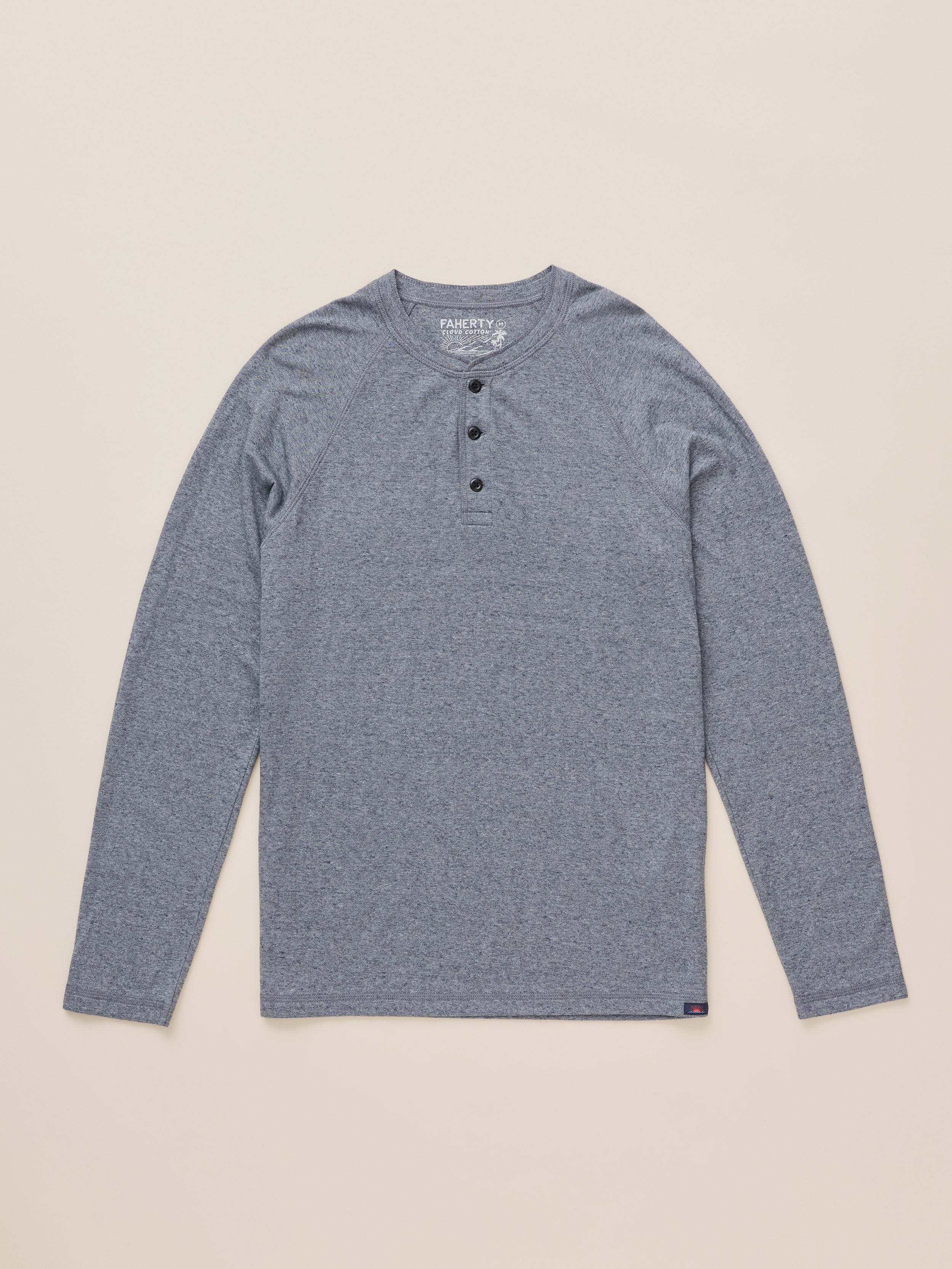 A heather gray long-sleeve henley shirt with three black buttons, laid flat on a light beige background.
