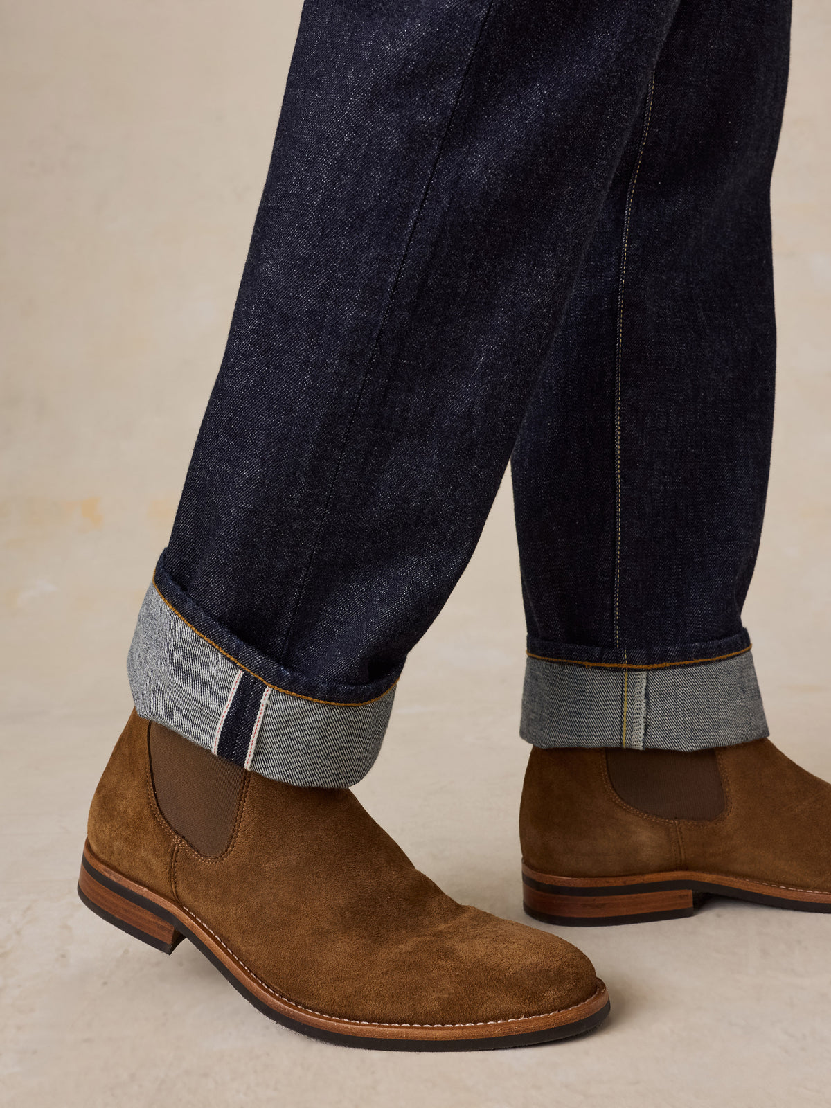 A man wearing brown suede boots with blue jeans, image 5 of 5