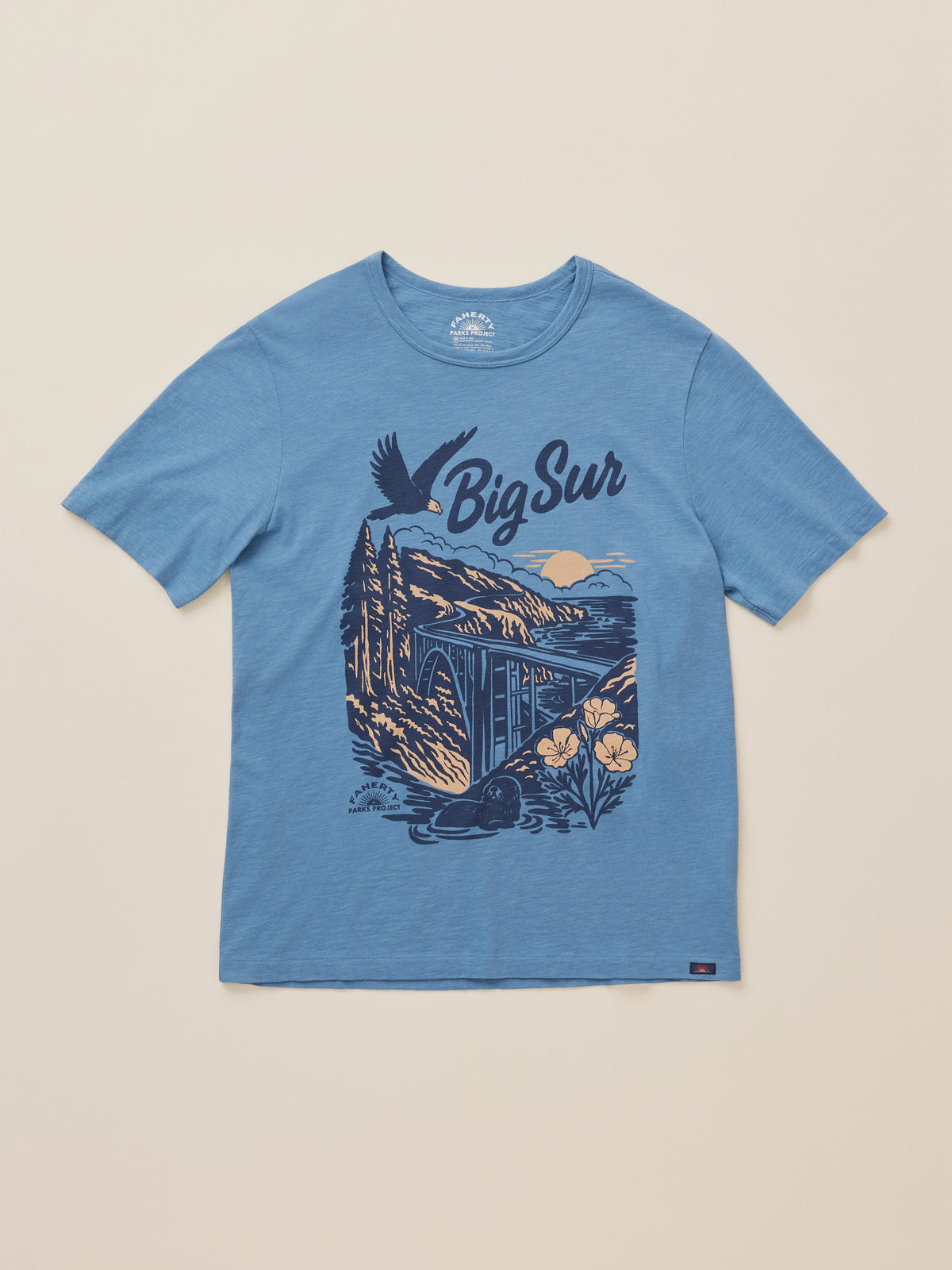 A heather blue short-sleeve t-shirt with a dark blue graphic print on the front featuring the text 'Big Sur' and an illustration of a coastal landscape, displayed flat against a light beige background., image 6 of 6