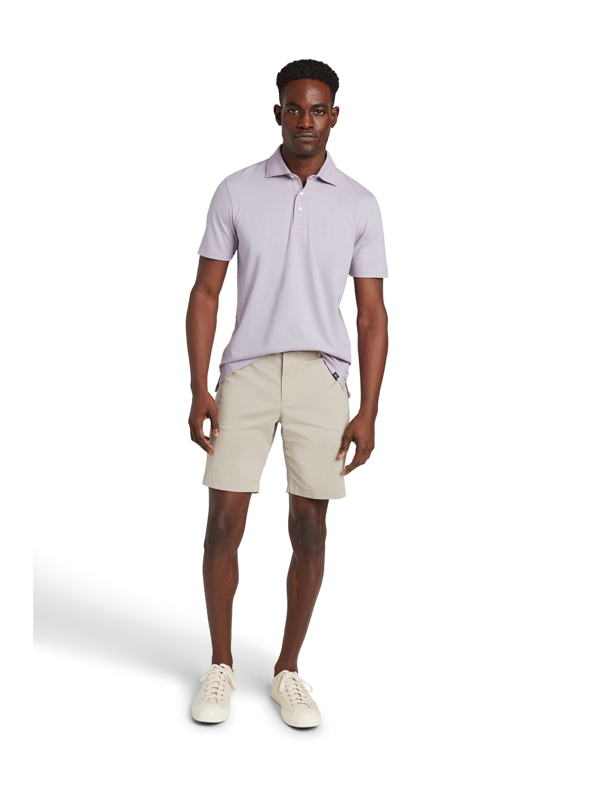 A man wearing a lavender polo, beige shorts, and sneakers, image 2 of 3