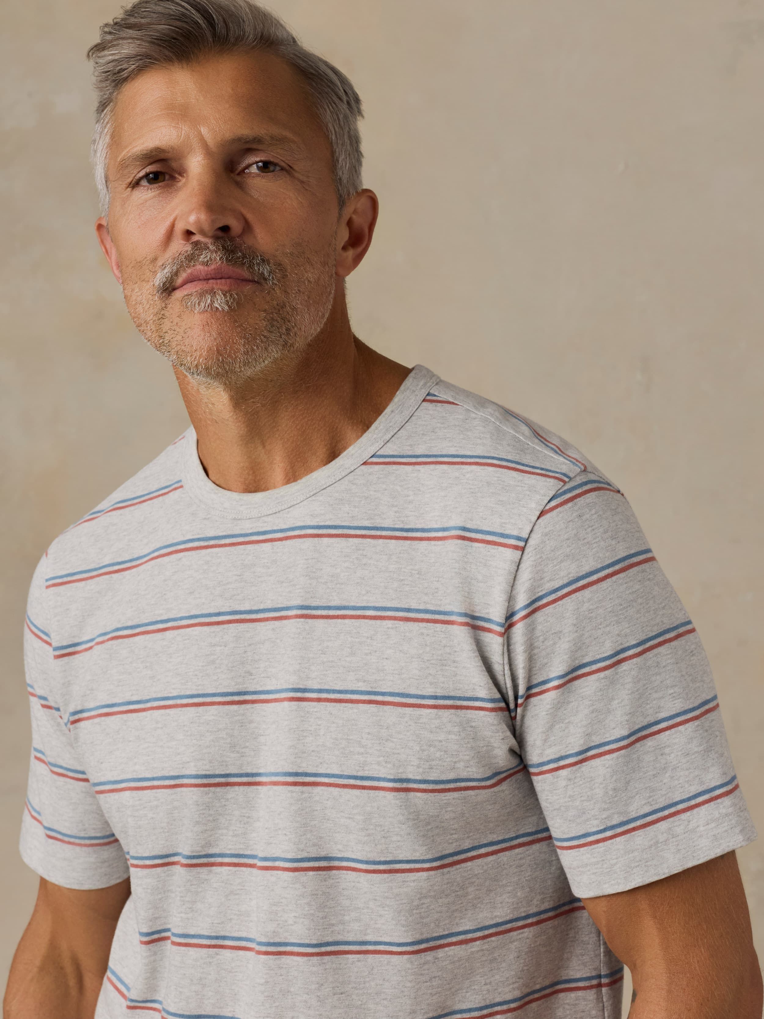 Man wearing a gray striped t-shirt against a beige background