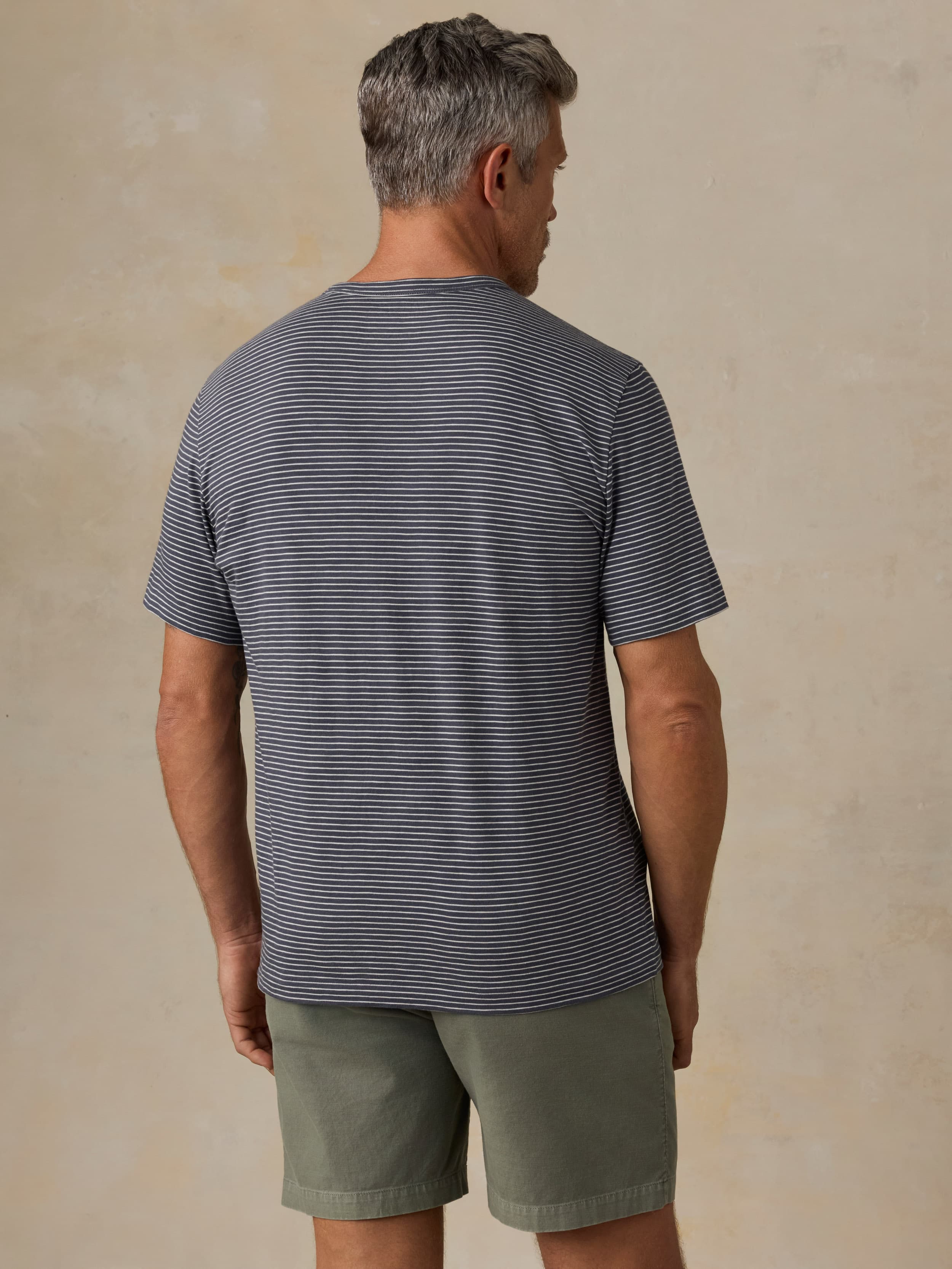 Man wearing a striped shirt and shorts against a beige background