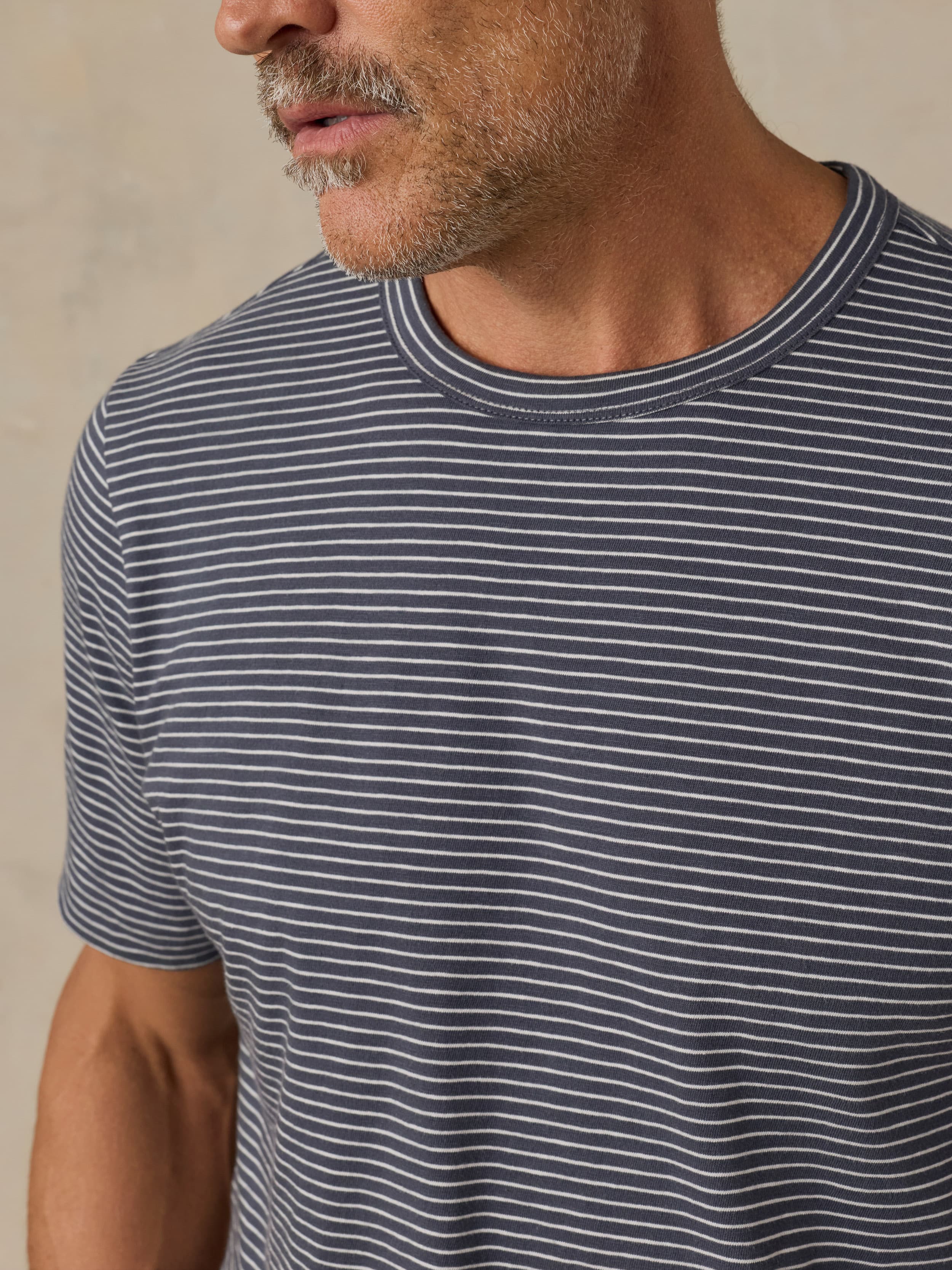 Man wearing a blue and white striped t-shirt against a beige background