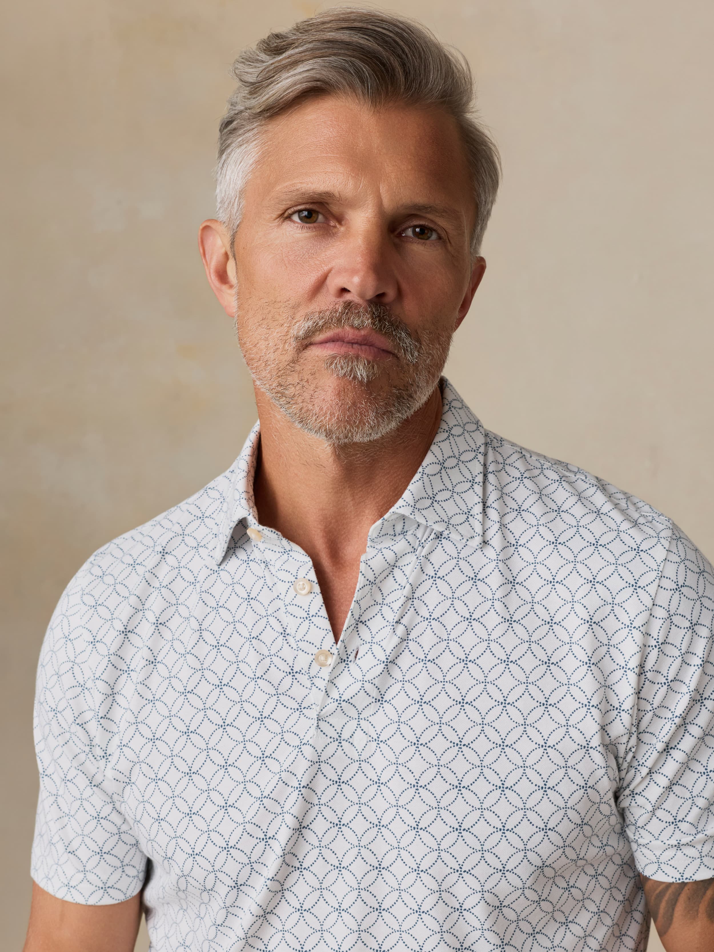 Man wearing a printed polo against a beige background