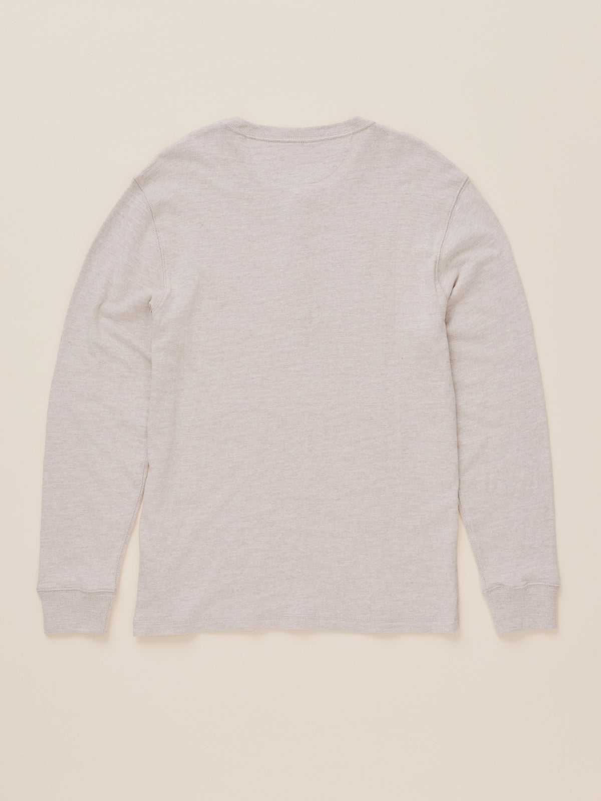 A light oatmeal heather long-sleeve t-shirt shown from the back, laid flat against a solid cream-colored background., image 8 of 8