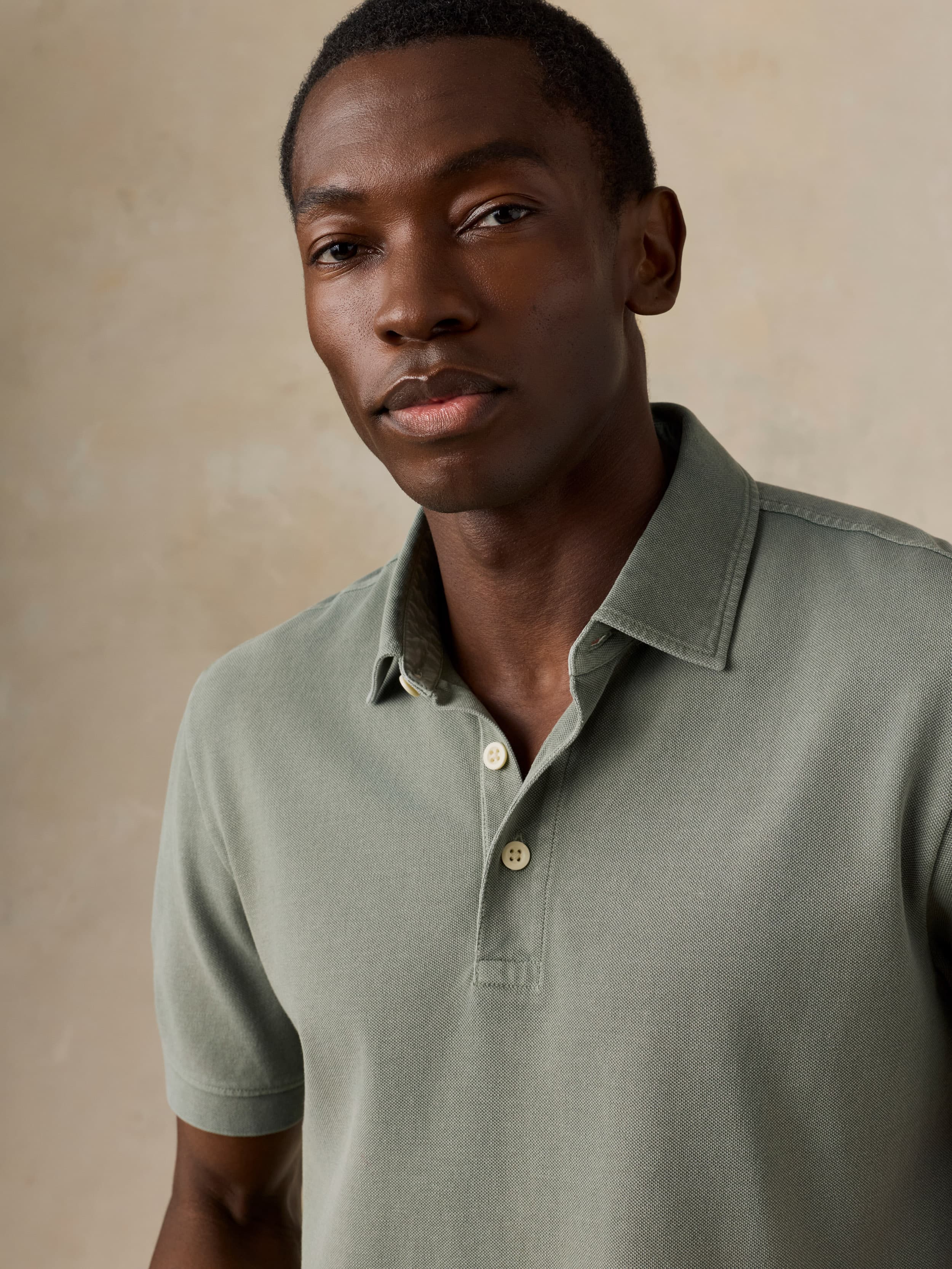 Man wearing a light green polo shirt against a beige background