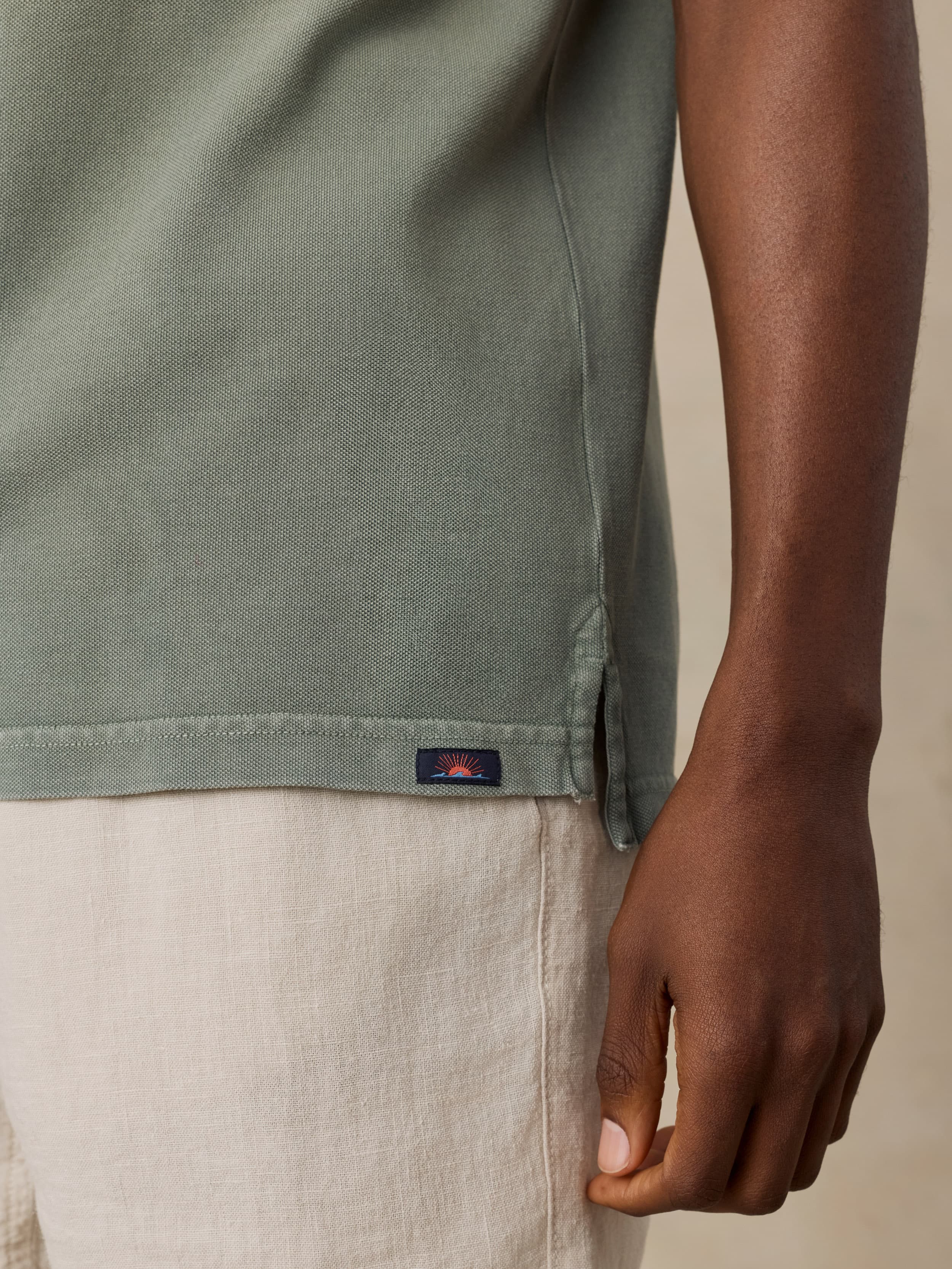 Man wearing a green t-shirt with a Faherty brand logo on a beige background