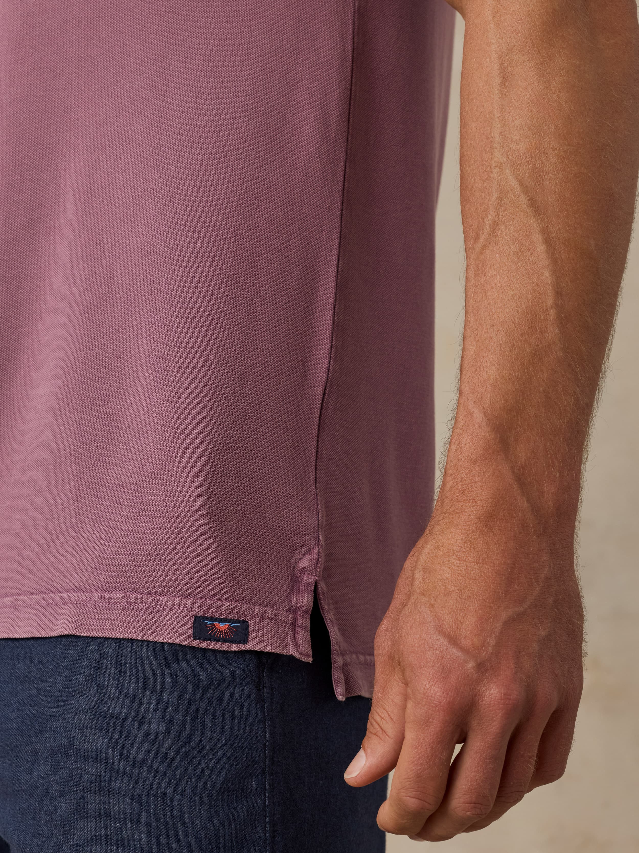 Close-up of a man wearing a purple polo shirt with a Faherty brand logo.