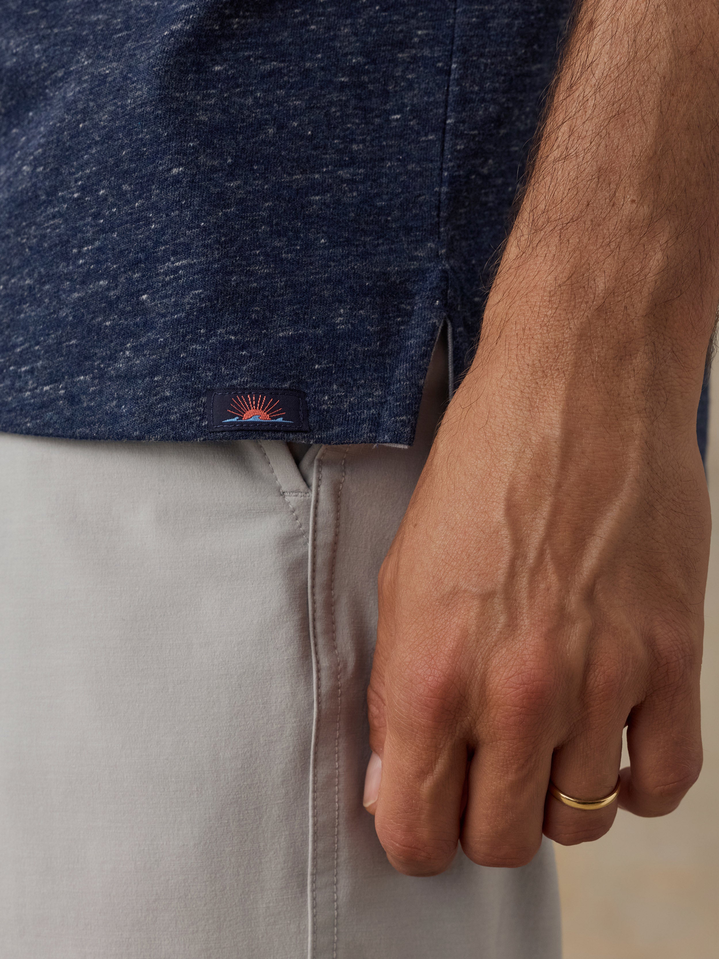 Close-up of a man wearing a blue shirt and beige pants on a beige background